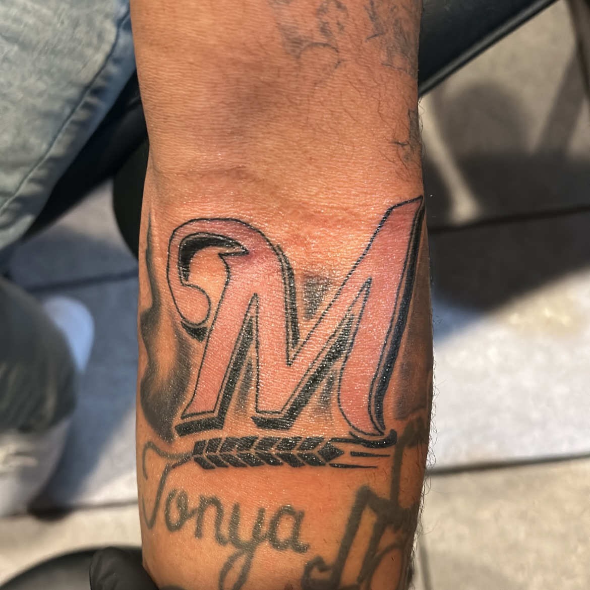 Flame letter M American traditional tattoo on the forearm by Tito Cross ❤️‍🔥
