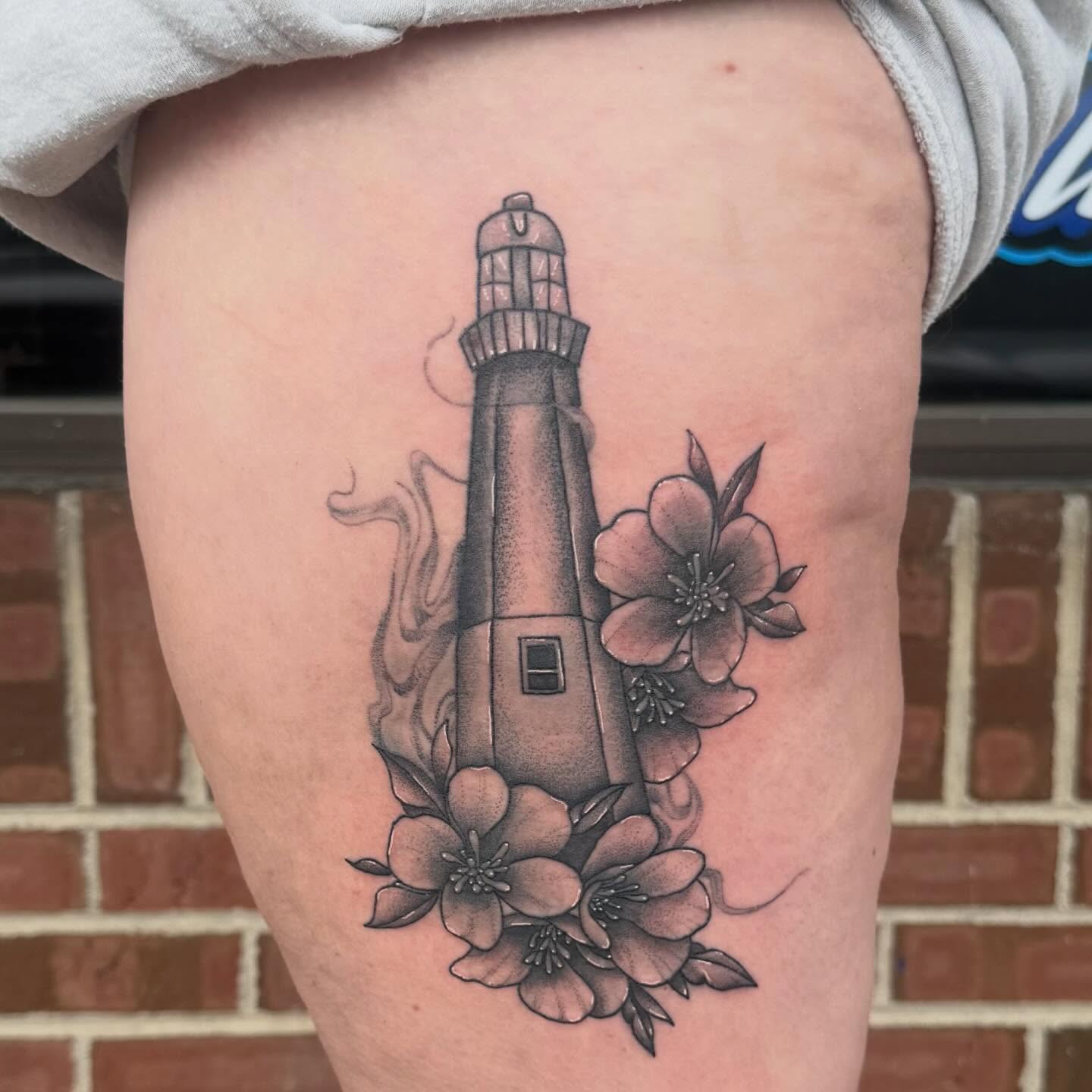 Lighthouse with flowers black and grey tattoo on the thigh by amelia morse ⋆。°✩ mi tattoo artist