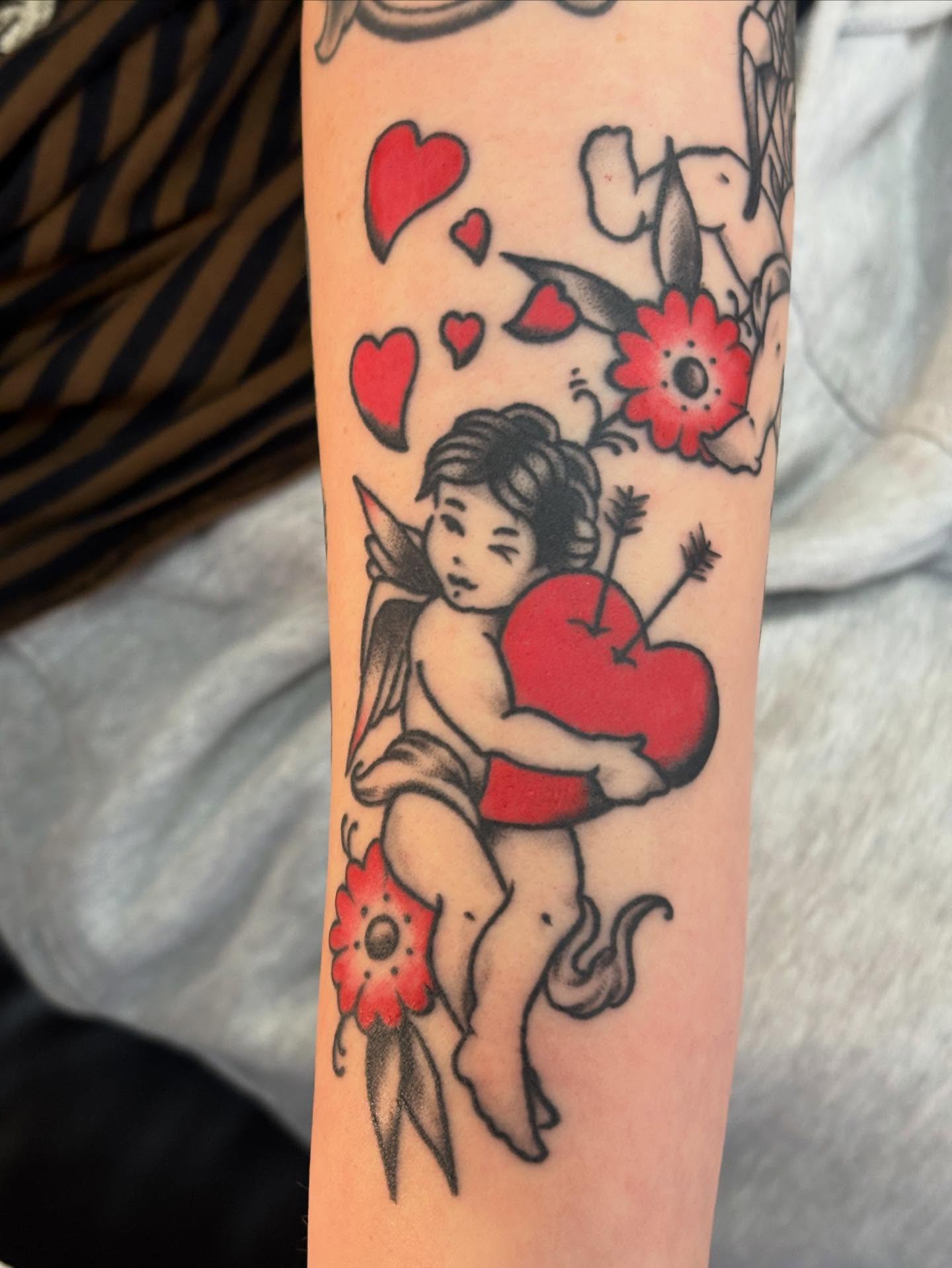Cupid holding heart American traditional tattoo on the forearm by Nick Tate