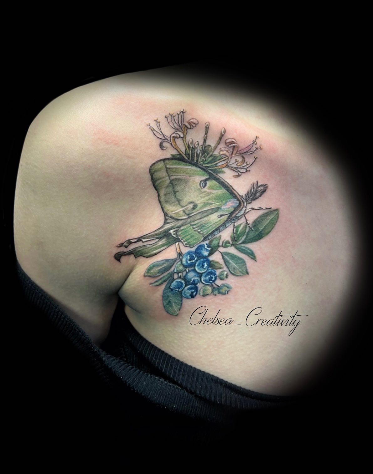 Moon moth and blueberries realism tattoo on the shoulder by Chelsea Nichole