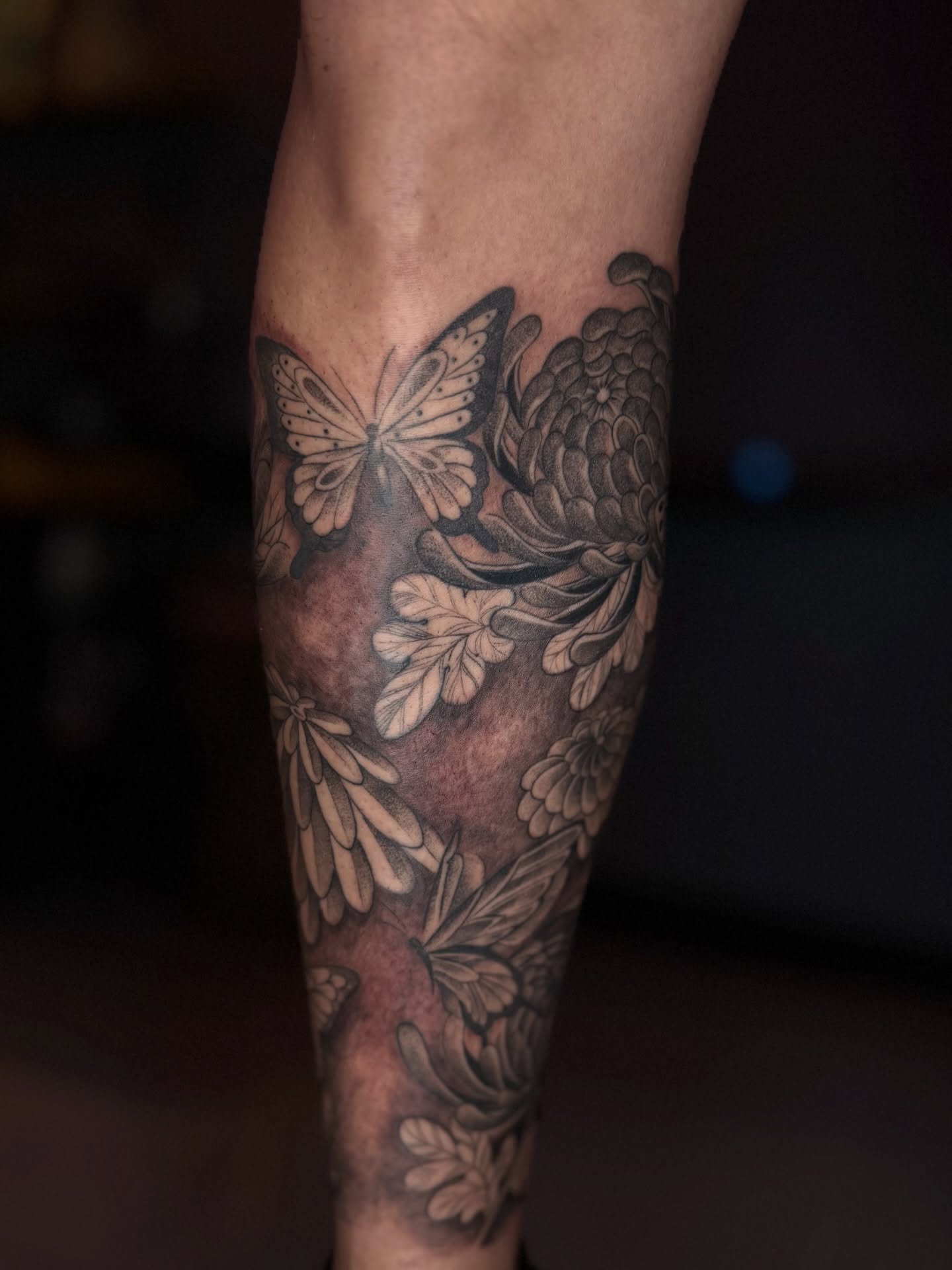 Butterfly and flowers black and grey tattoo on the forearm by B o n d B o n d , “ a r t i s t “
