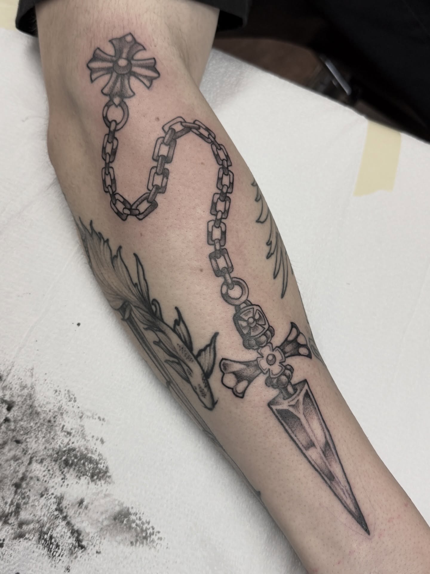 Chain and cross black and grey tattoo on the forearm by Jeremy Utley