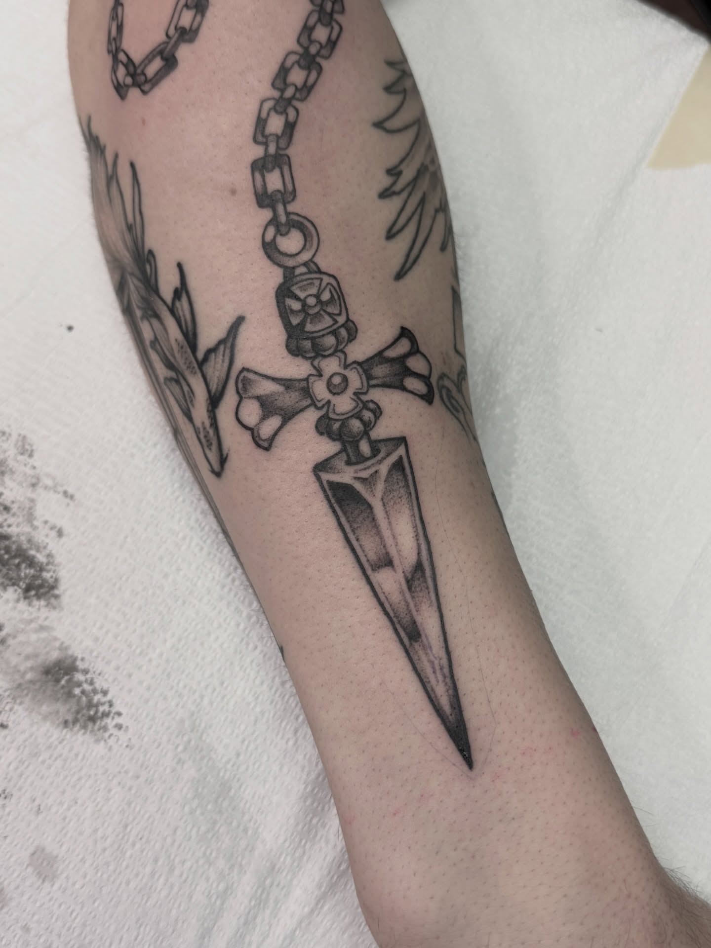 Crossed bones and dagger black and grey tattoo on the forearm by Jeremy Utley