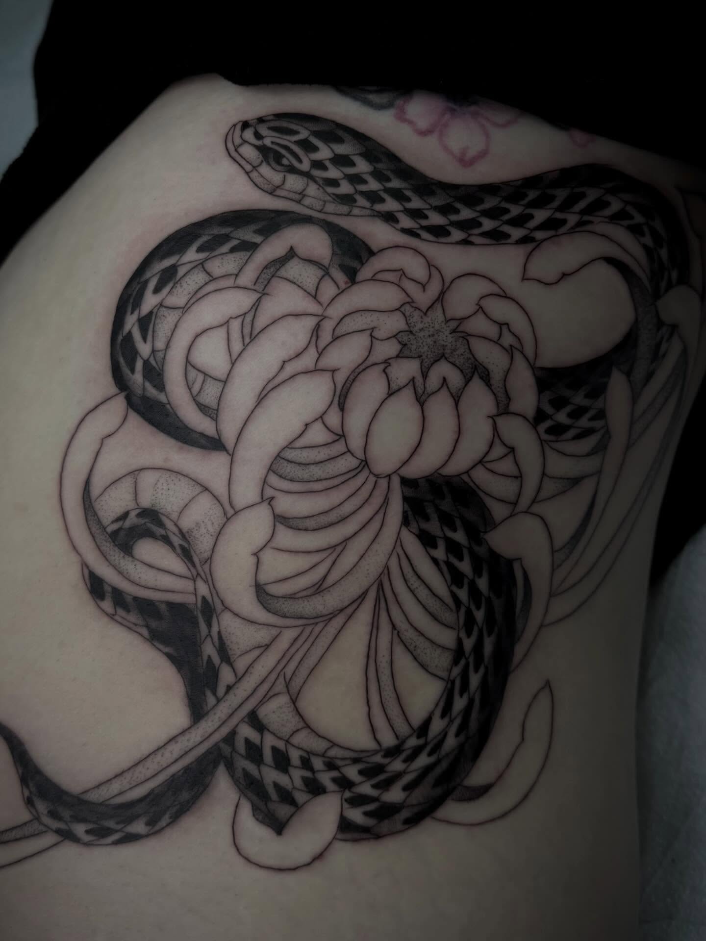 Snake and chrysanthemum black and grey tattoo on the thigh by christian martinez