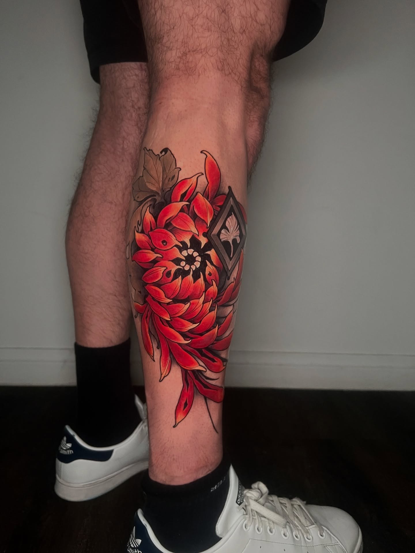Red flower new school tattoo on the calf by Joshua Weeks