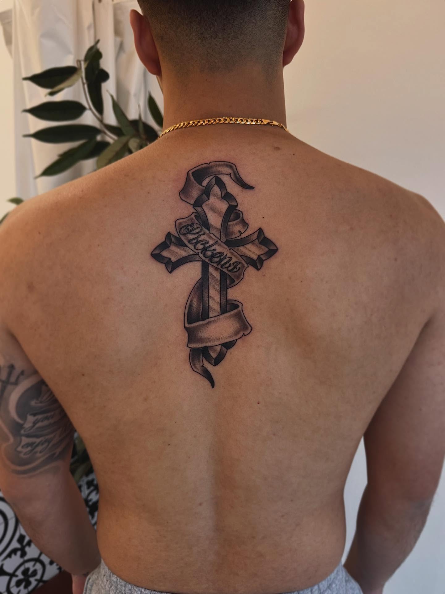 Cross with ribbon black and grey tattoo on the back by Stefany