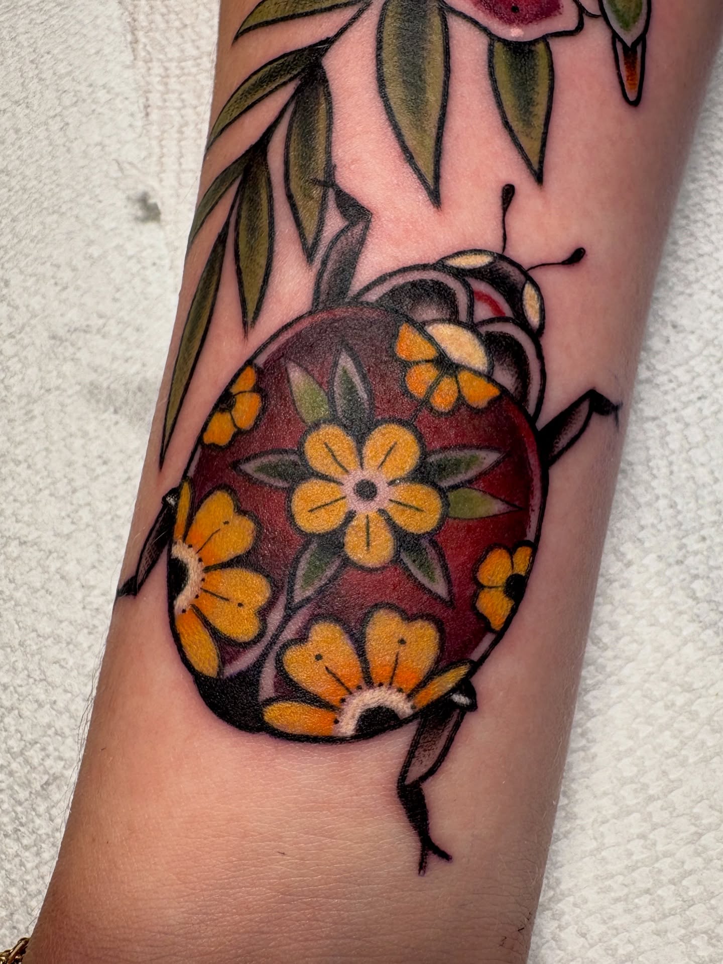 Beetle with floral pattern new school tattoo on the forearm by Josh Johns