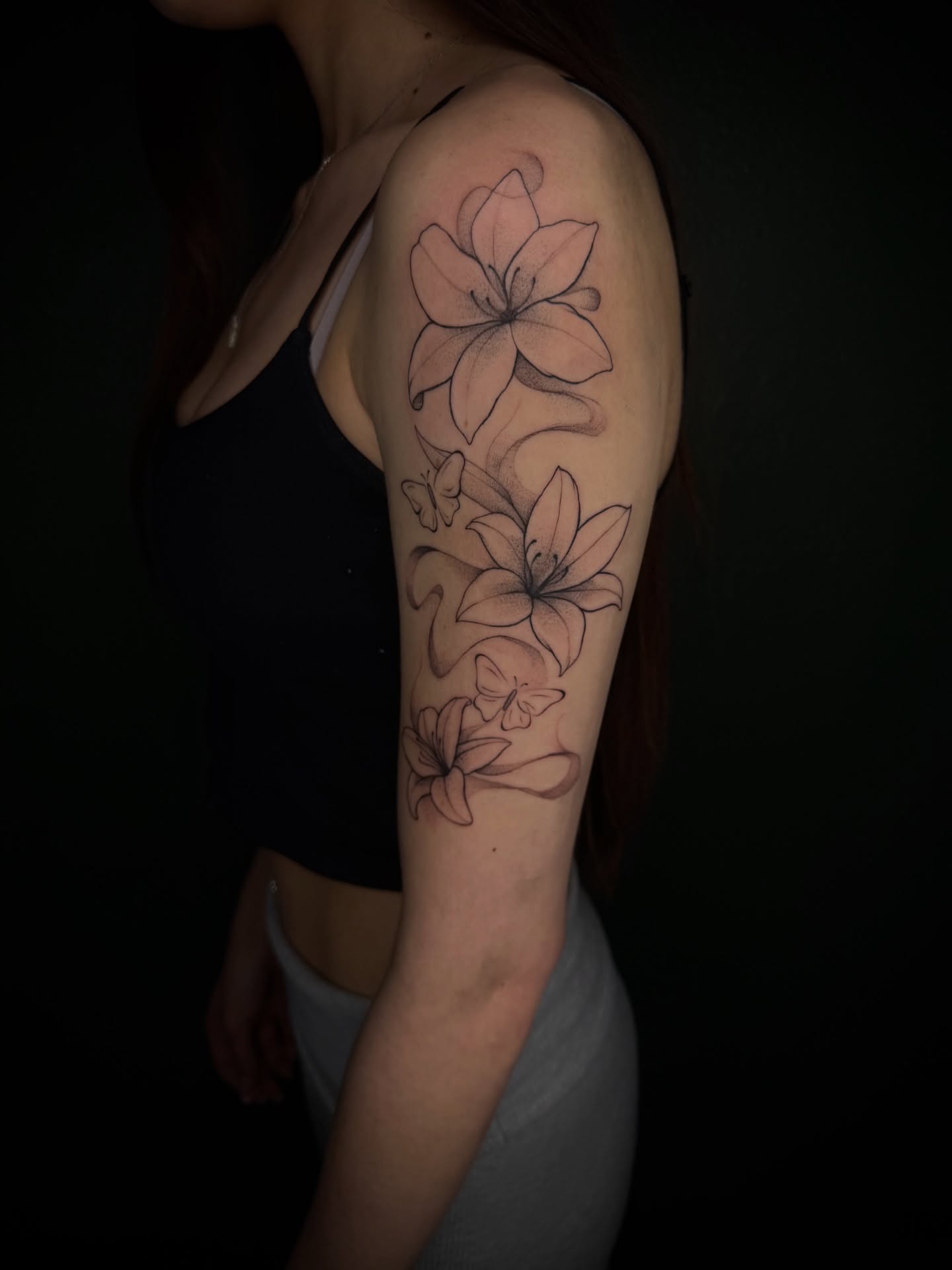 Lilies black and grey tattoo on the upper arm by Marcus