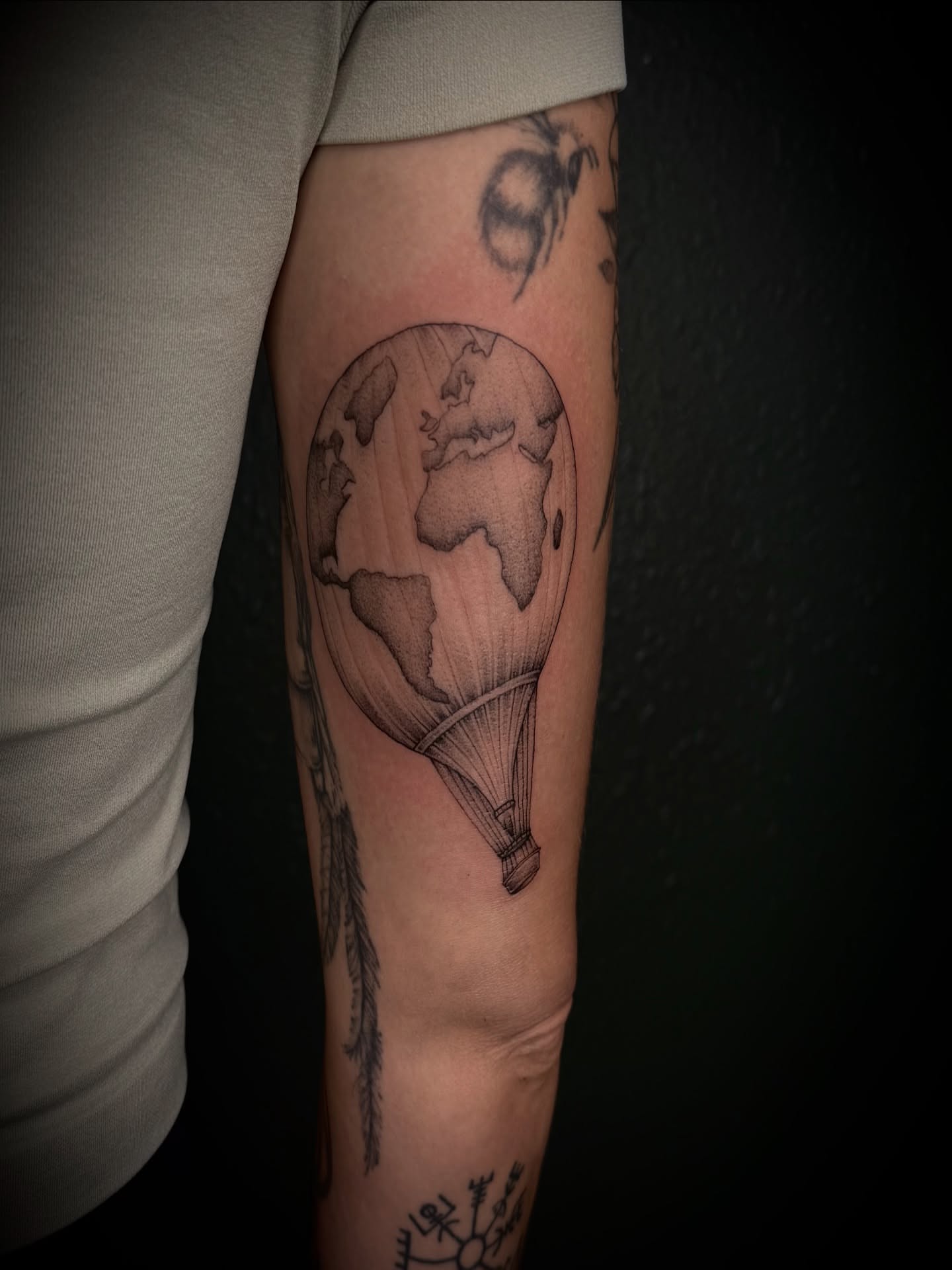 Hot air balloon with Earth black and grey tattoo on the forearm by Marcus