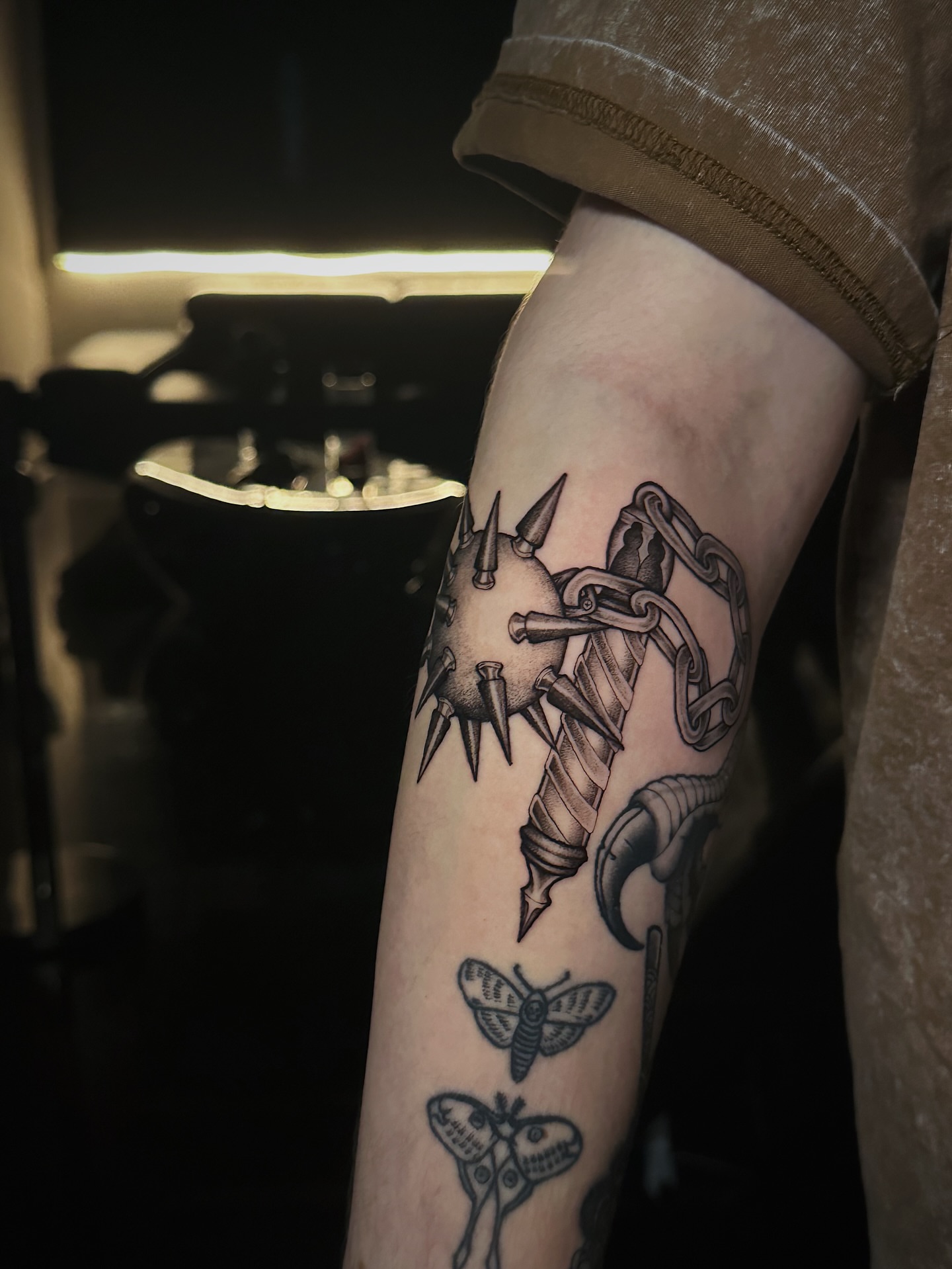Spiked ball and chain black and grey tattoo on the forearm by Kelsey Zussman