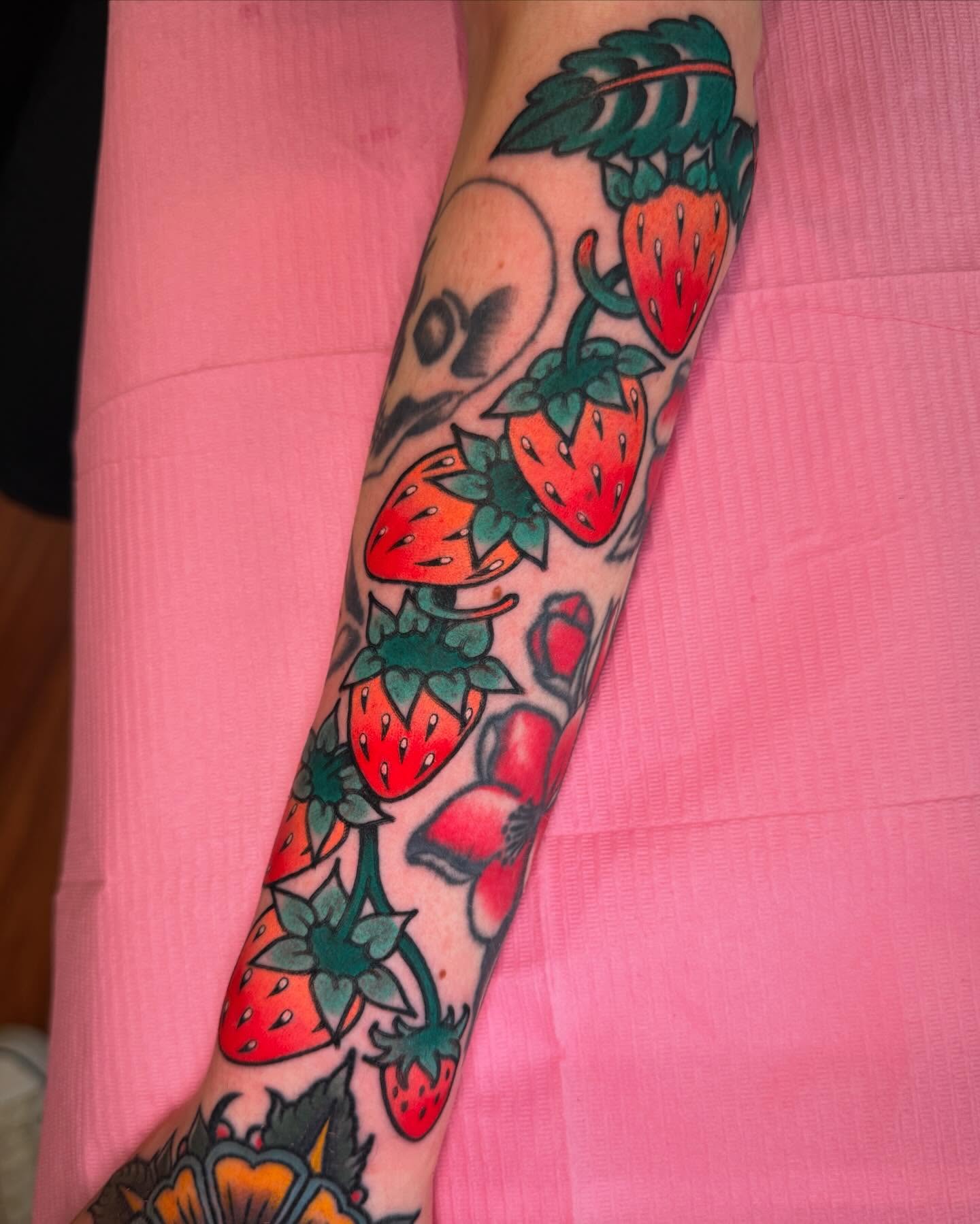 Strawberries and flowers American traditional tattoo on the forearm by Cassie O'Neal DeBord