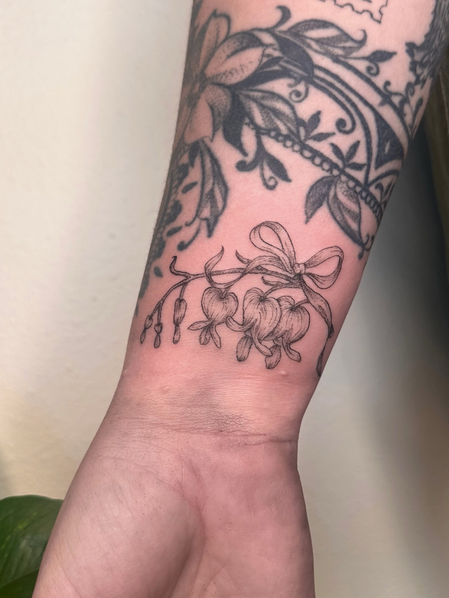 Bell-shaped flowers black and grey tattoo on the forearm by kenzie hunter