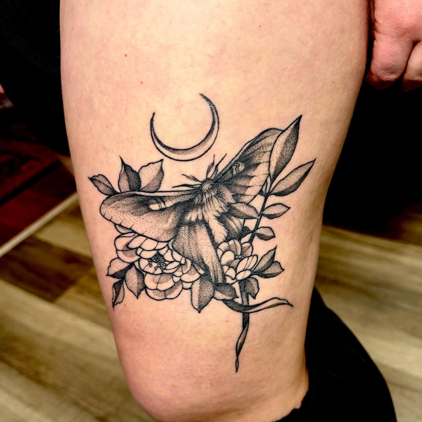 Moth and flowers dotwork tattoo on the thigh by Emily