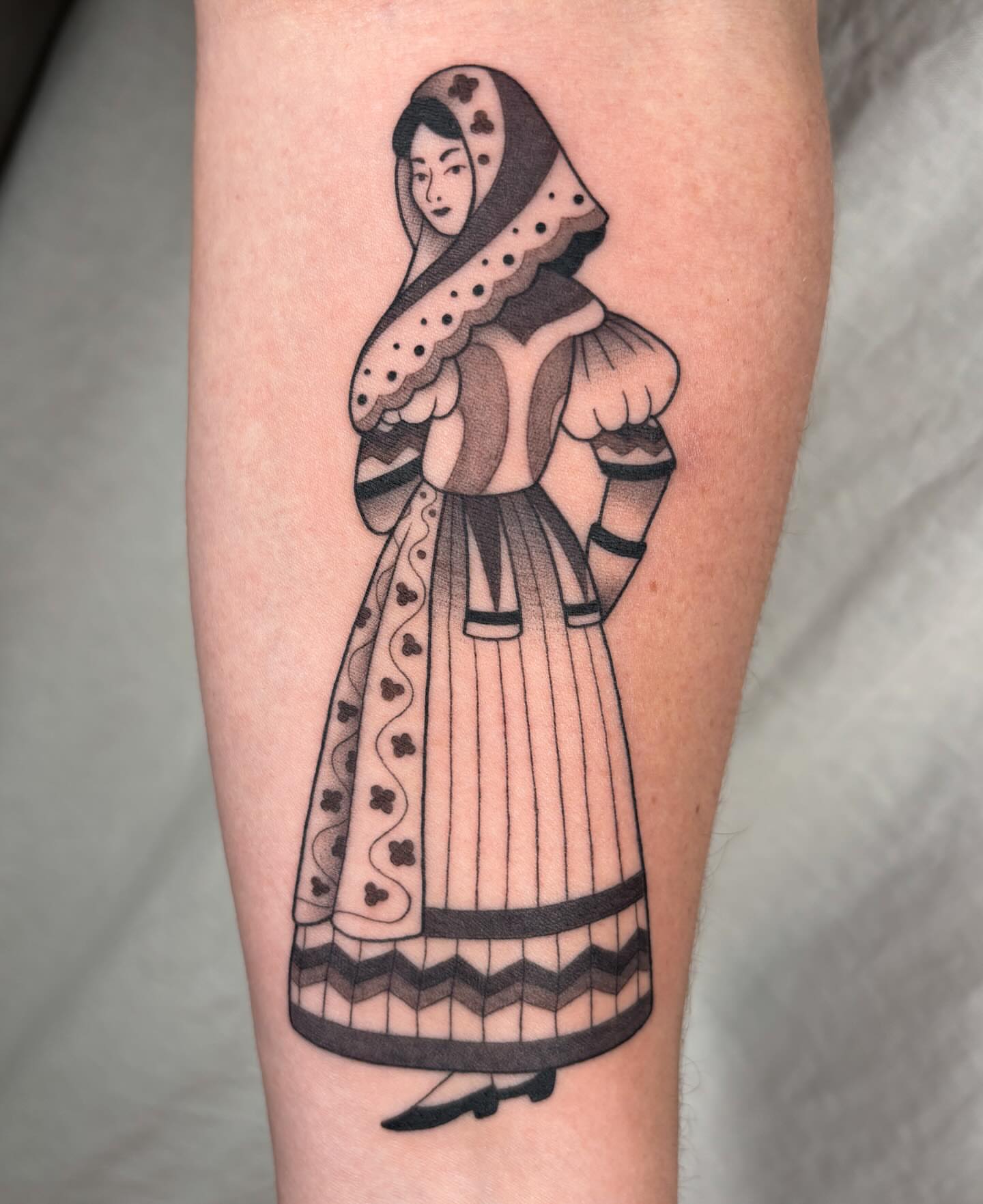 Woman in historical attire black and grey tattoo on the forearm by Anna Sage