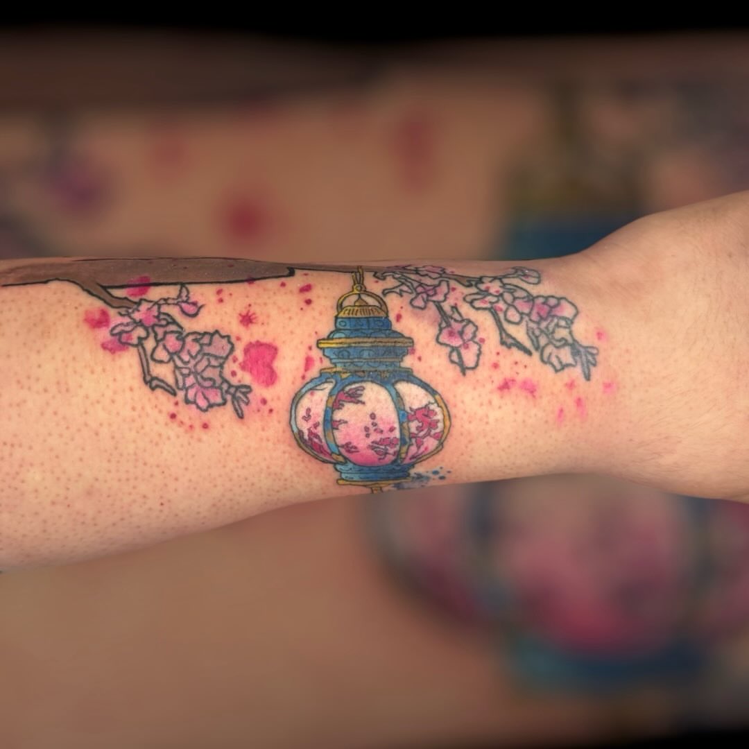 Cherry blossoms and lantern watercolor tattoo on the forearm by Paula.p.tattoos