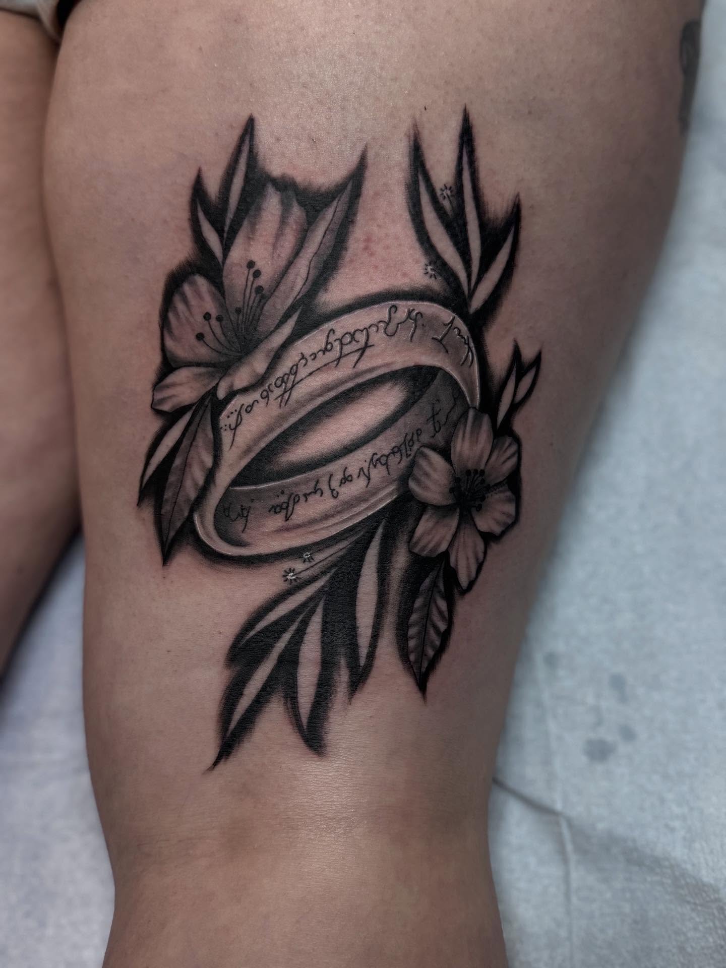Flower and ribbon black and grey tattoo on the thigh by Jacob - Tattoo Artist