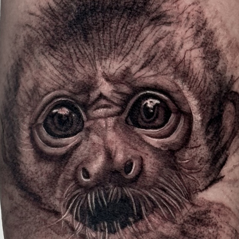 Monkey face dark art tattoo on the forearm by Brisia Cisneros