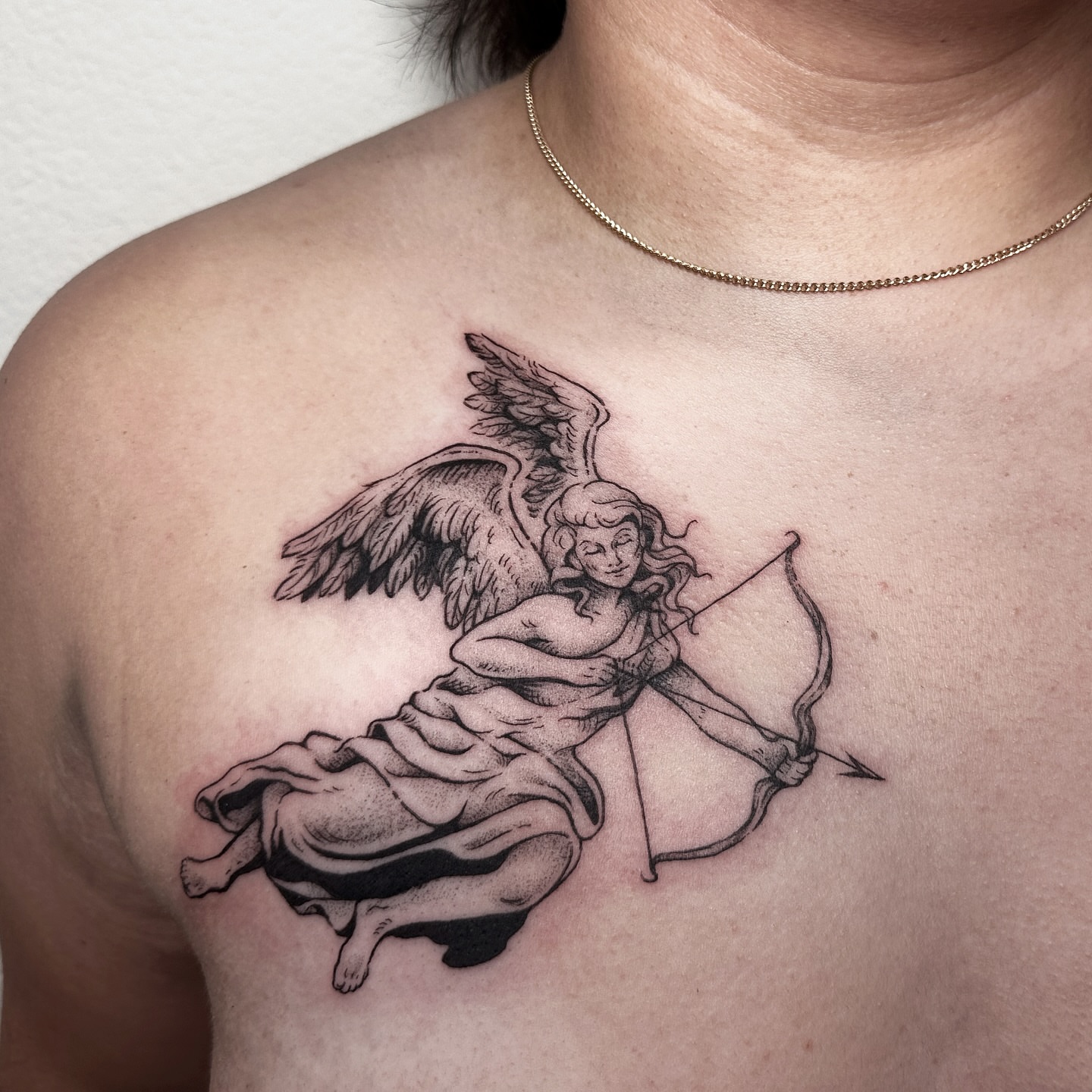 Angel with bow black and grey tattoo on the chest by Micky, Austin, Texas