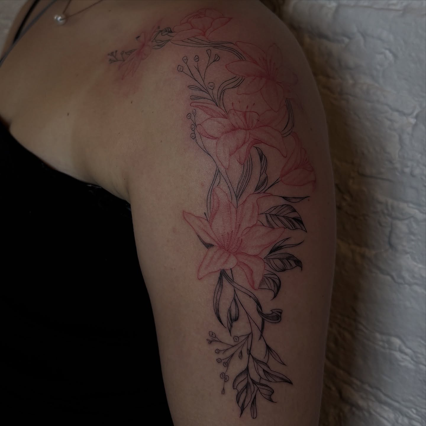 Lily flowers black and grey tattoo on the upper arm by Sydney Gallucci