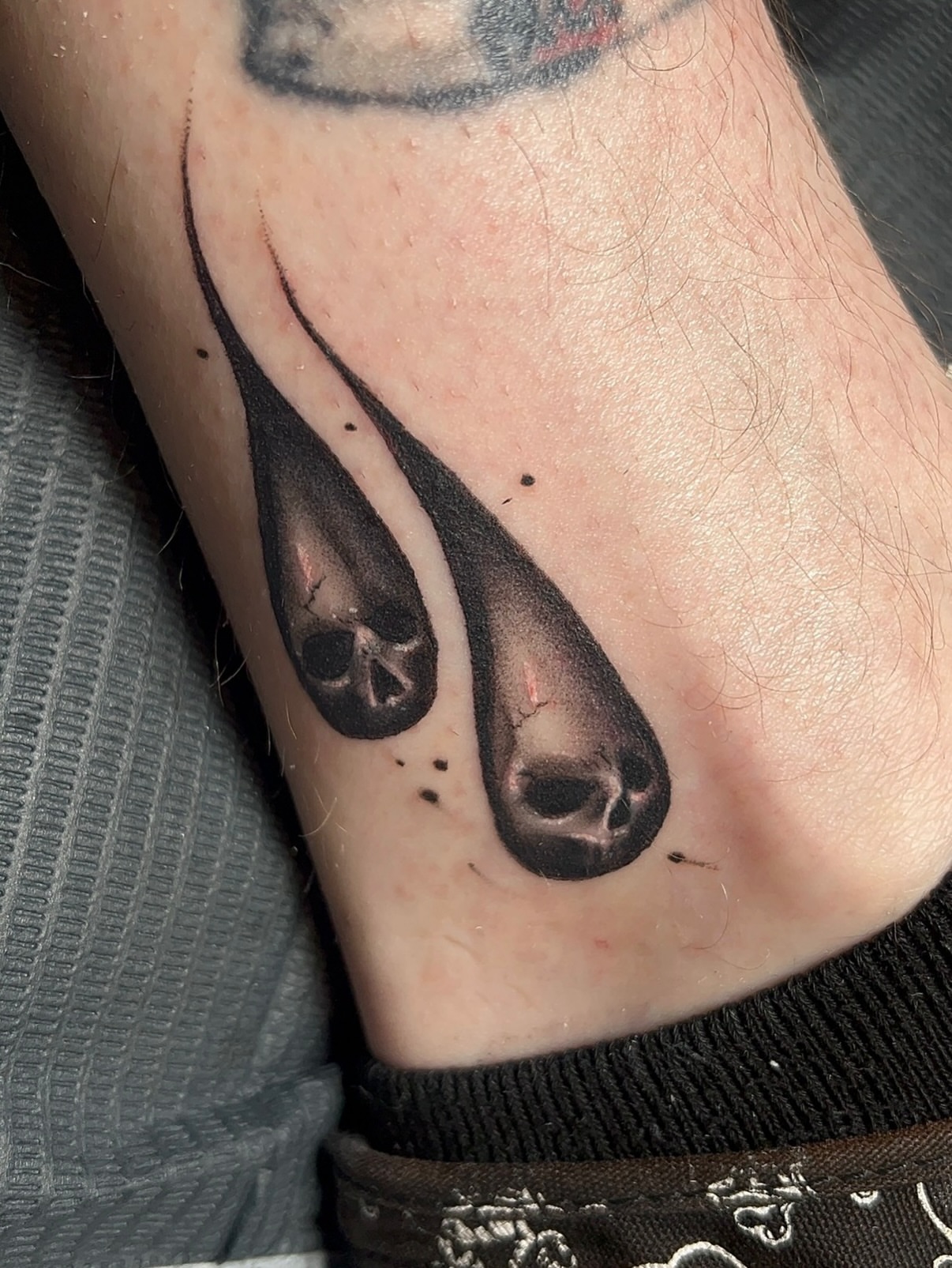 Tears with skulls realism tattoo on the forearm by Denis Seregin