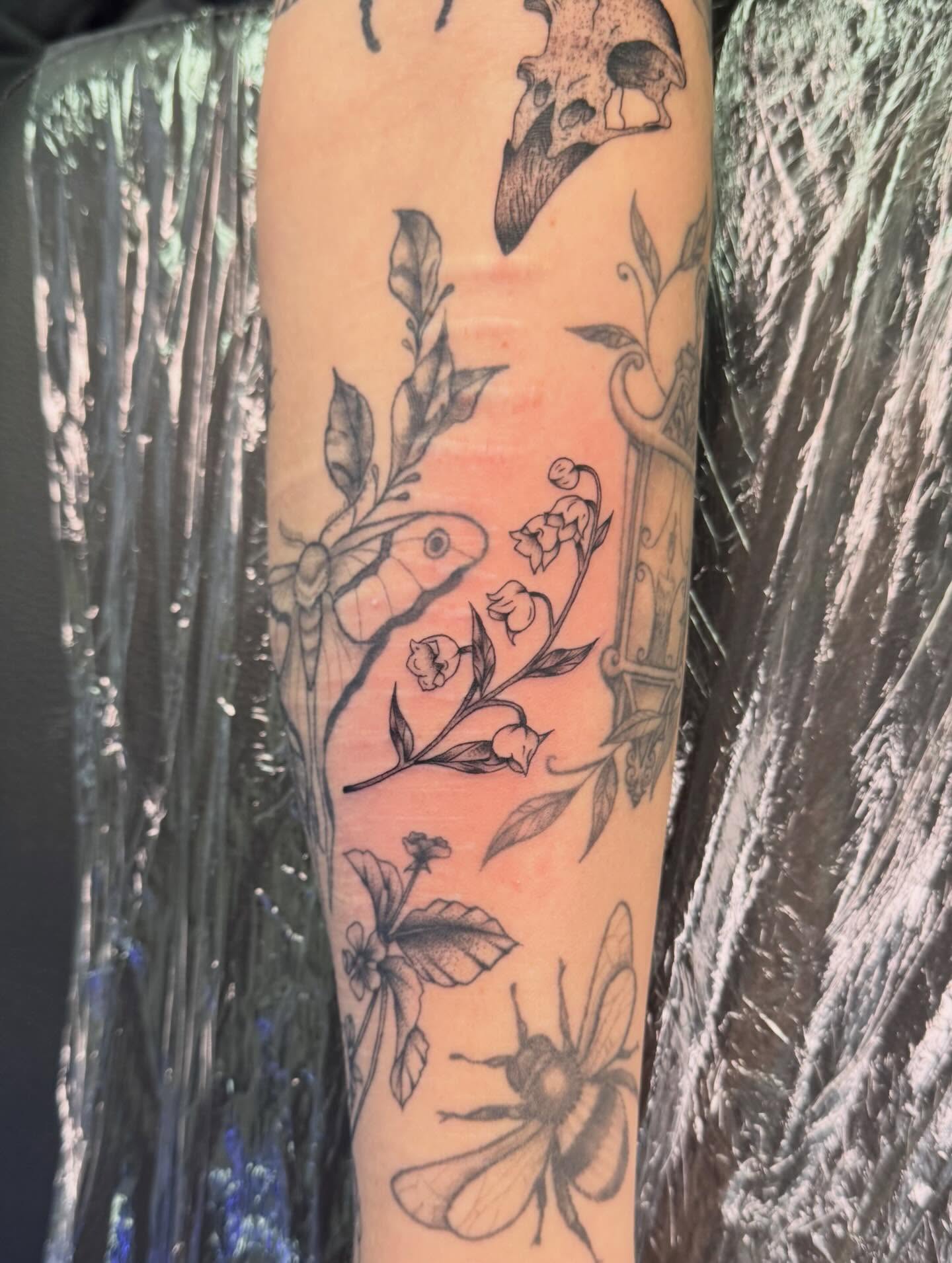 Botanical and insect motifs black and grey tattoo on the forearm by haylie