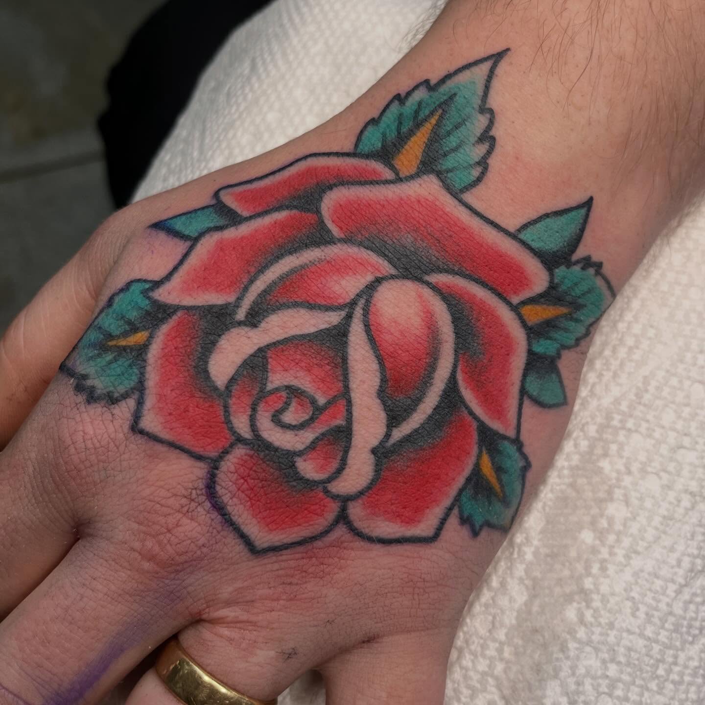 Rose American traditional tattoo on the hand by ๐๐ฎ๐ฌ๐ญ๐ข๐ง ๐๐จ๐ฐ๐๐ซ๐, Oakland, California