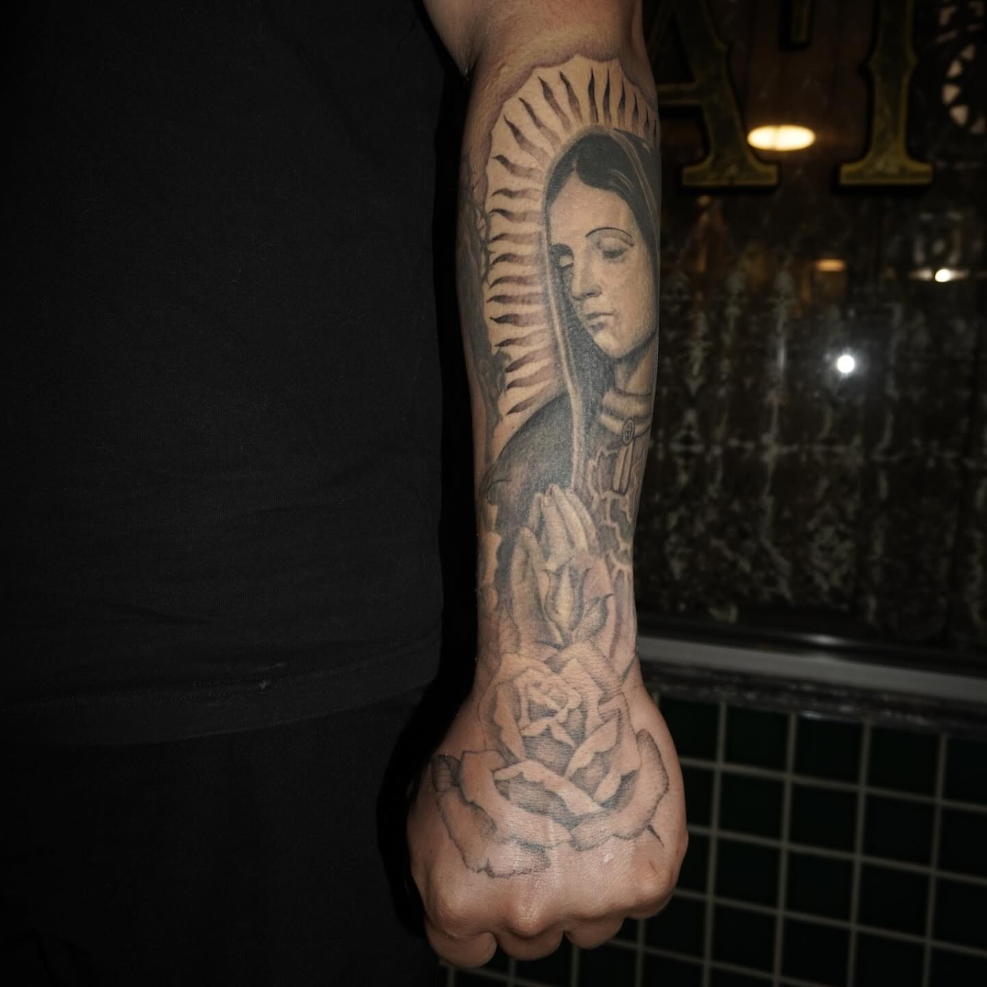 Religious figure with roses realism tattoo on the forearm by San Diego tattoo artist