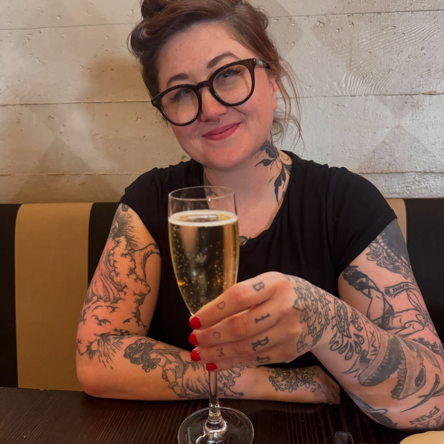 Champagne flute black and grey tattoo on the upper arm by Lora Bird