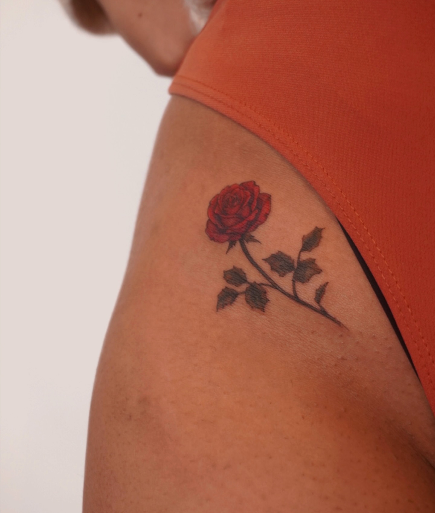 Red rose realism tattoo on the upper arm by Sun Child Tattoo 🌻