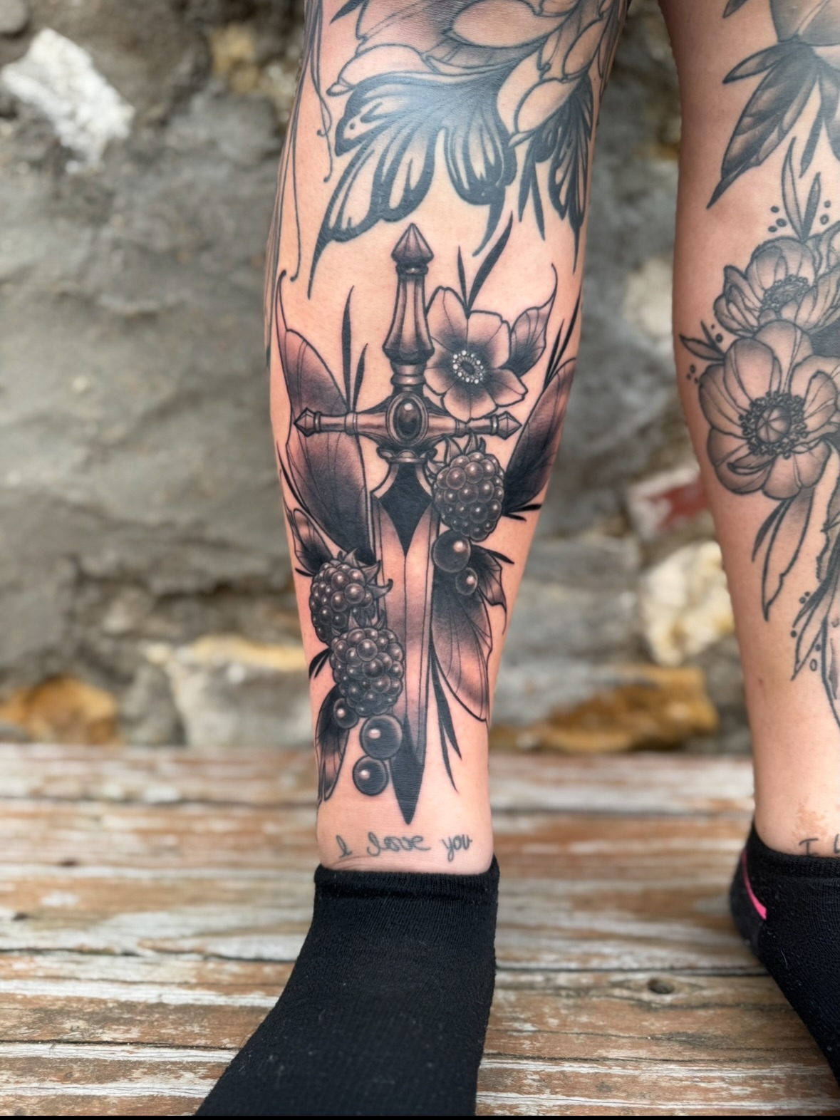 Cross and flowers black and grey tattoo on the calf by Erin Bratzler