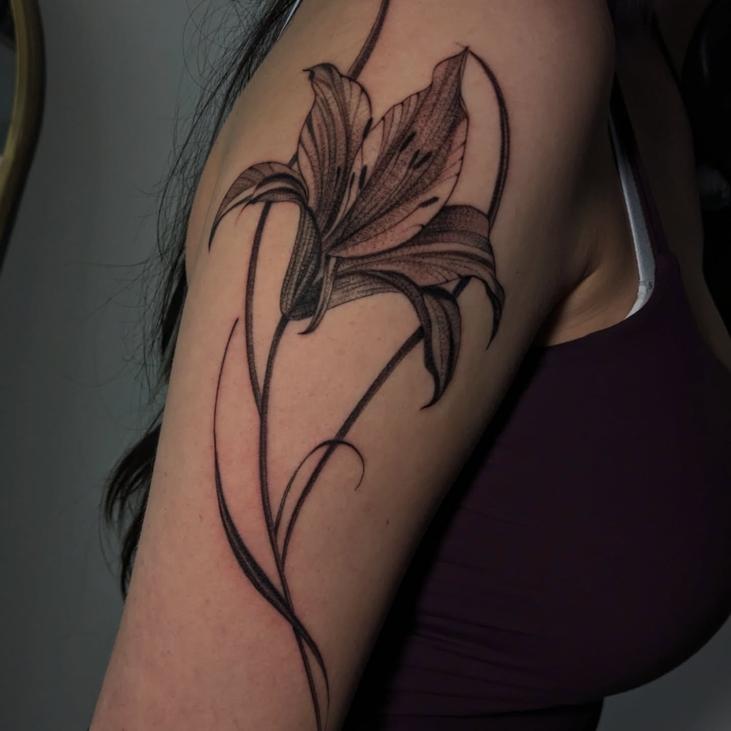 Lily dotwork tattoo on the upper arm by Jasmine Dillon