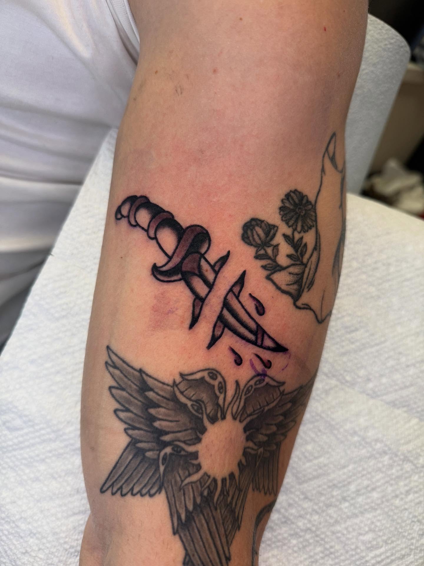 Sword and flowers black and grey tattoo on the forearm by Cody Petkus