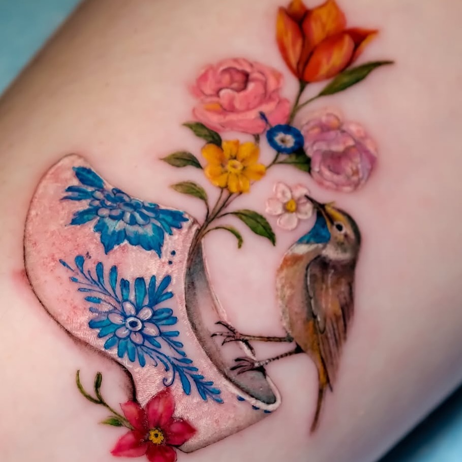 Bird and floral arrangement realism tattoo on the upper arm by NAS
