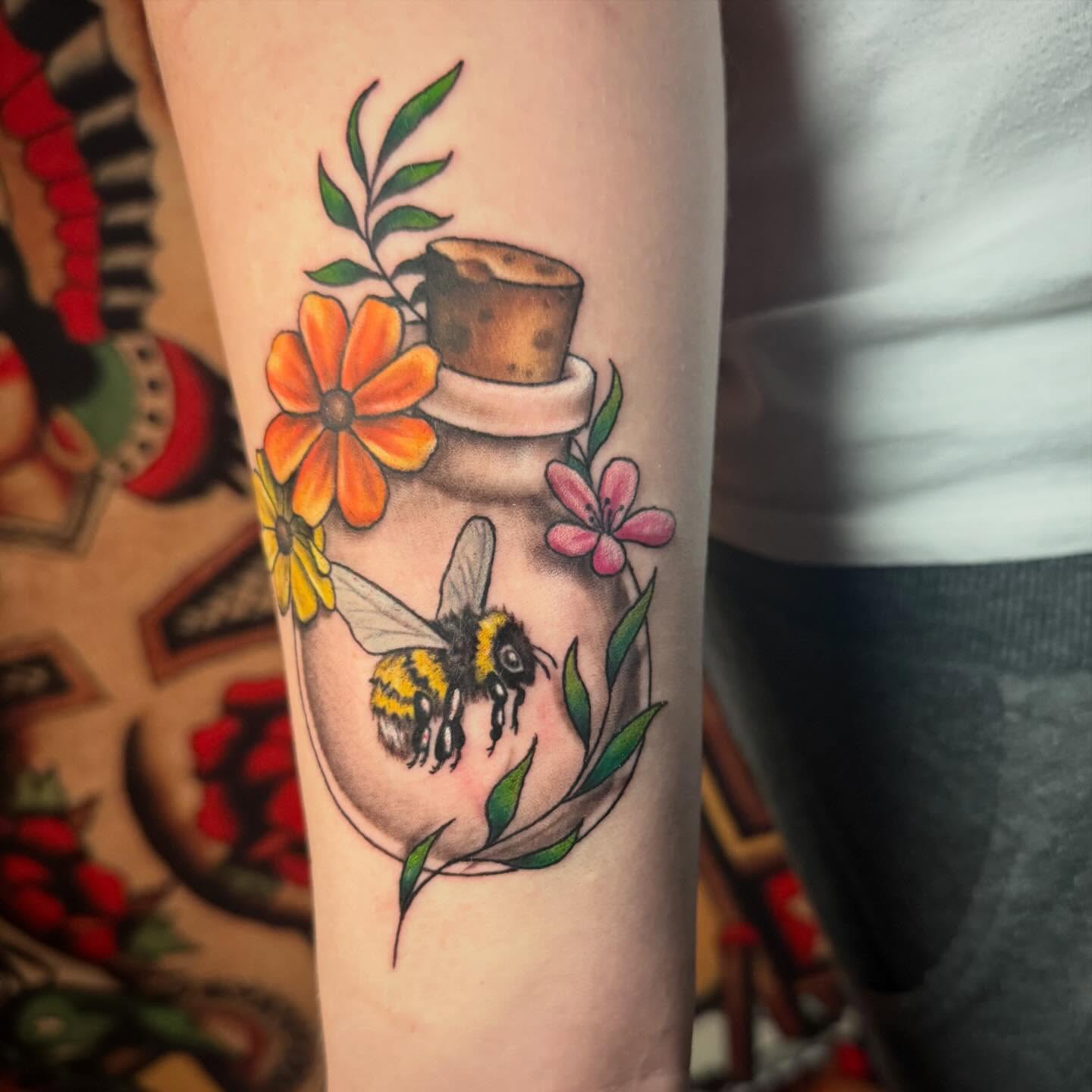 Bee and bottle American traditional tattoo on the forearm by Alexis Monkiewicz
