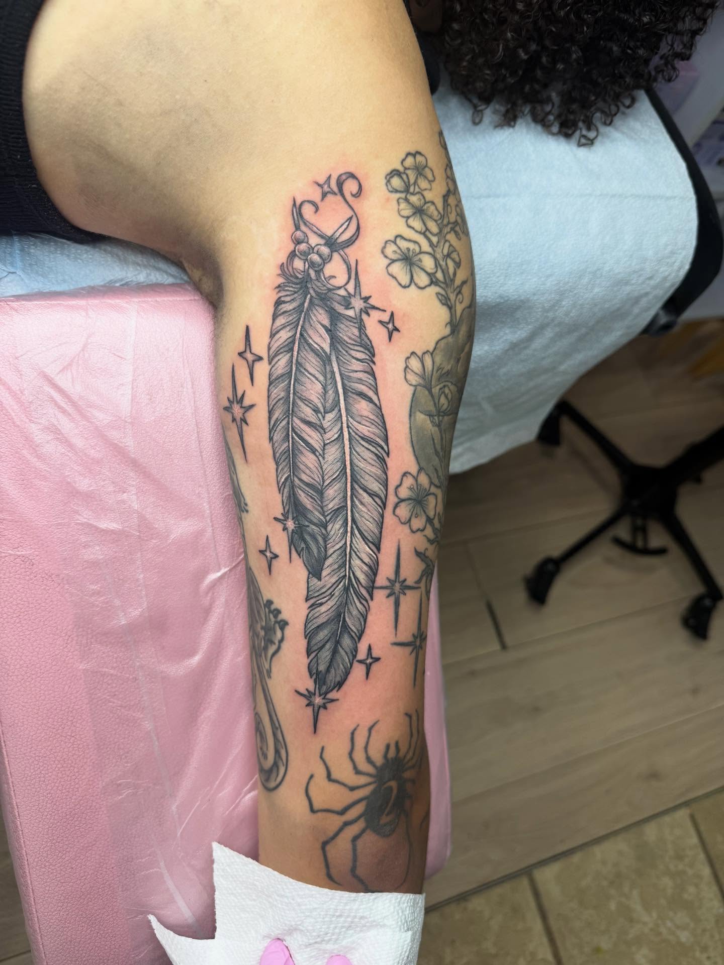 Feather and flowers black and grey tattoo on the forearm by Bry