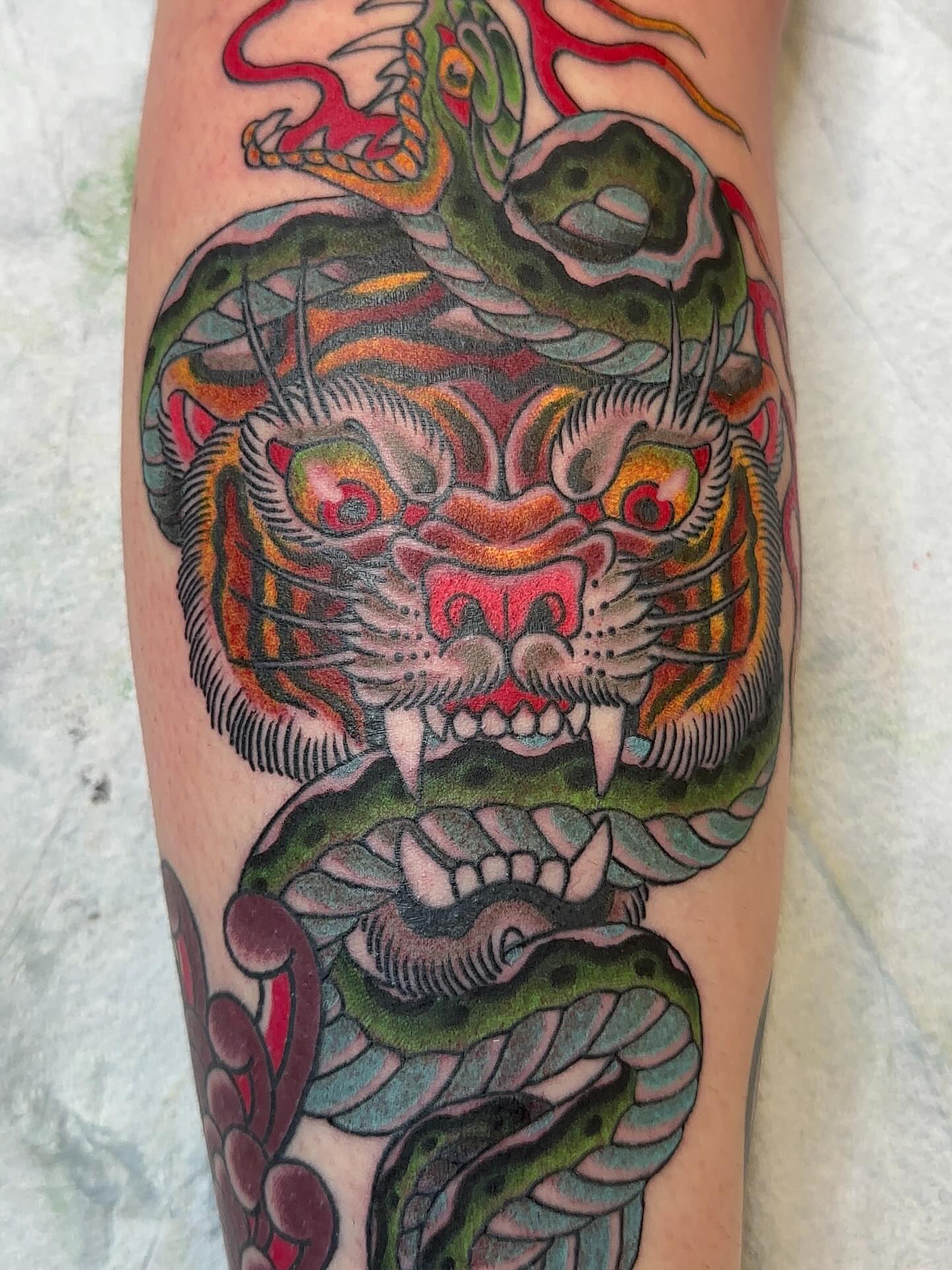Tiger and snake American traditional tattoo on the forearm by Cody Hanson