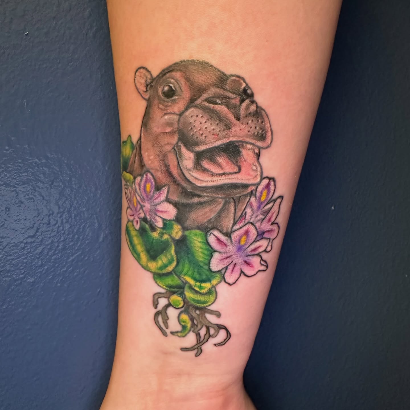 Hippo with flowers realism tattoo on the forearm by Maggie De La Torre ๐ณ๏ธโโง๏ธ๐ฒ๐ฝ