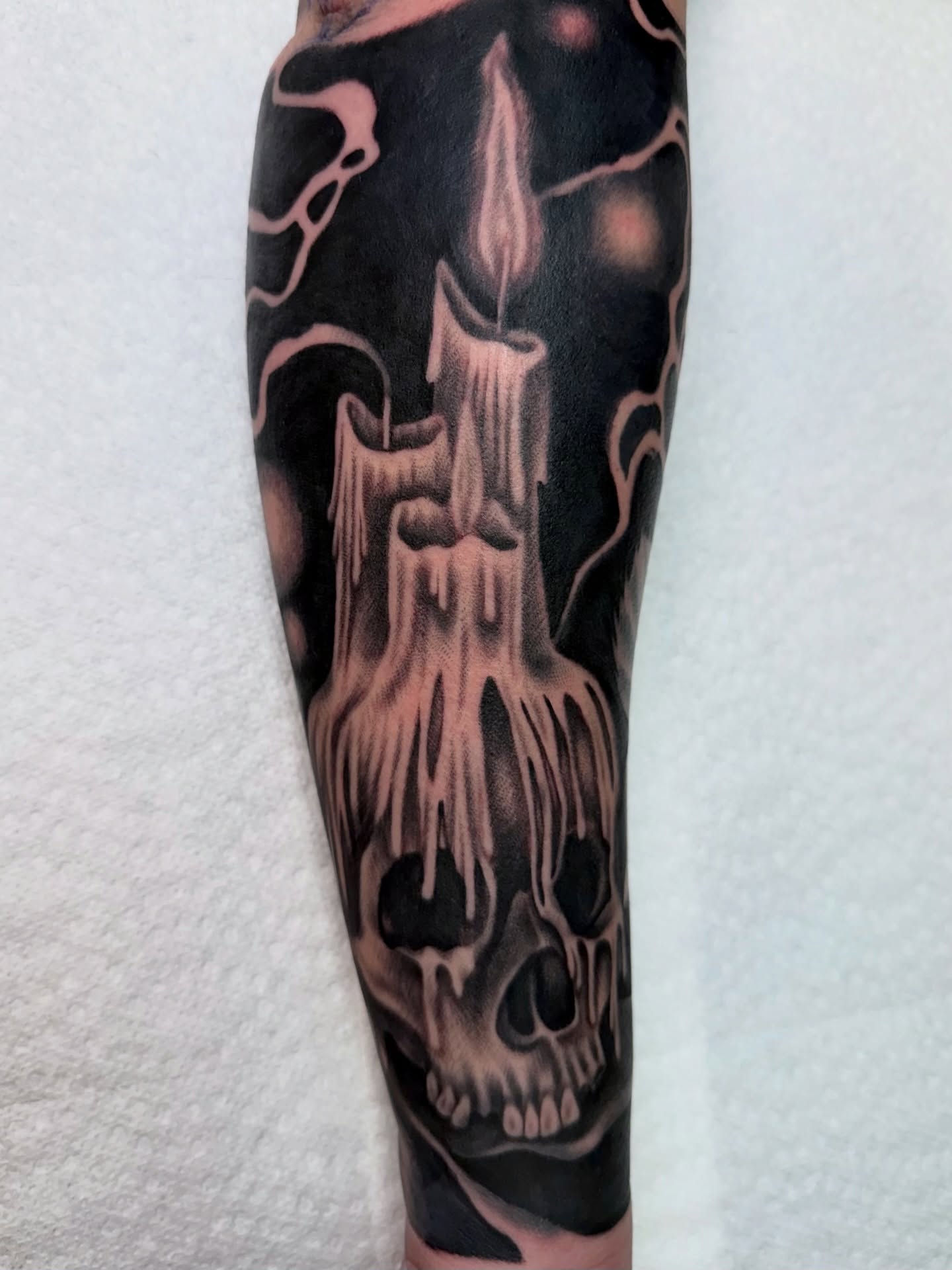 Skull and candle dark realism tattoo on the forearm by Savannah Compton