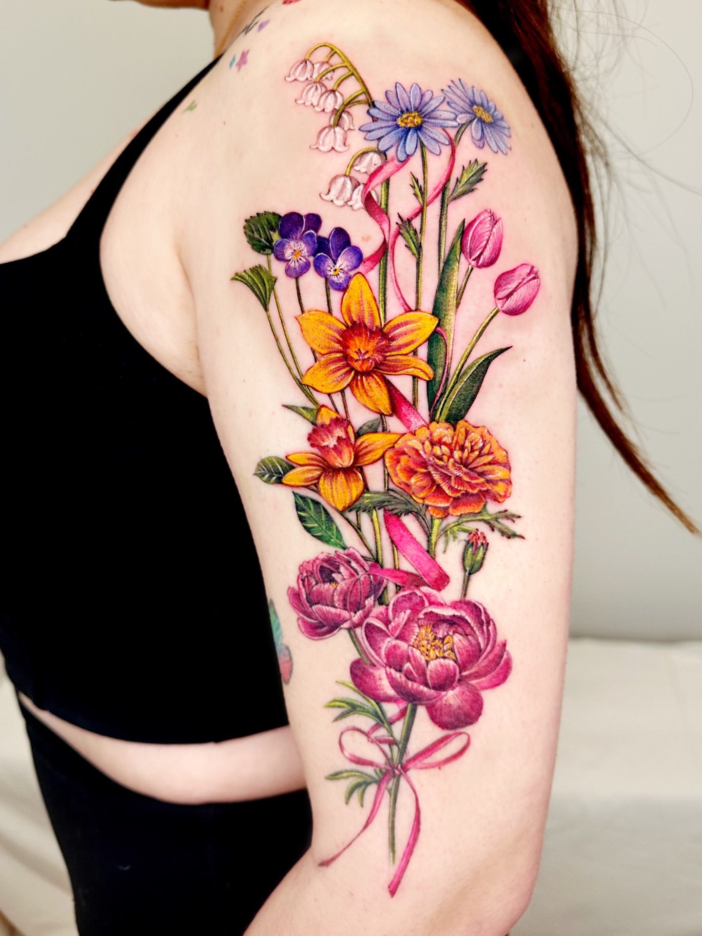 Floral bouquet realism tattoo on the upper arm by Claire