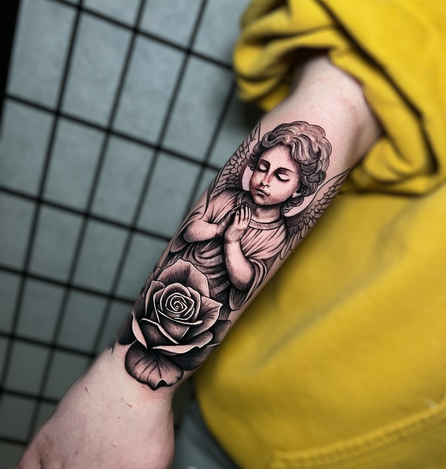Angel with roses black and grey tattoo on the forearm by Tattoo Artist
