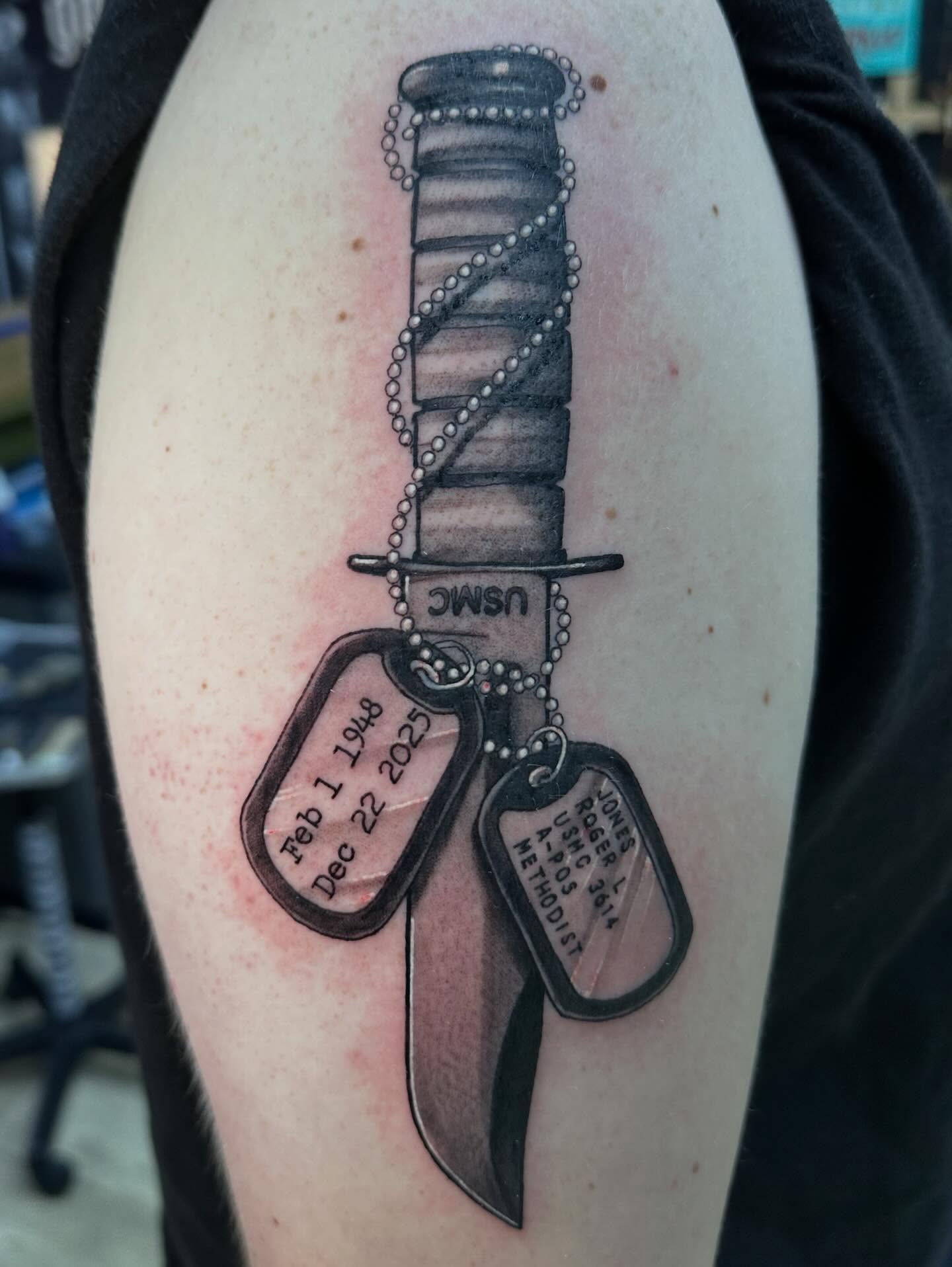 Knife and dog tags black and grey tattoo on the upper arm by Dustin Clark, Dayton, Ohio
