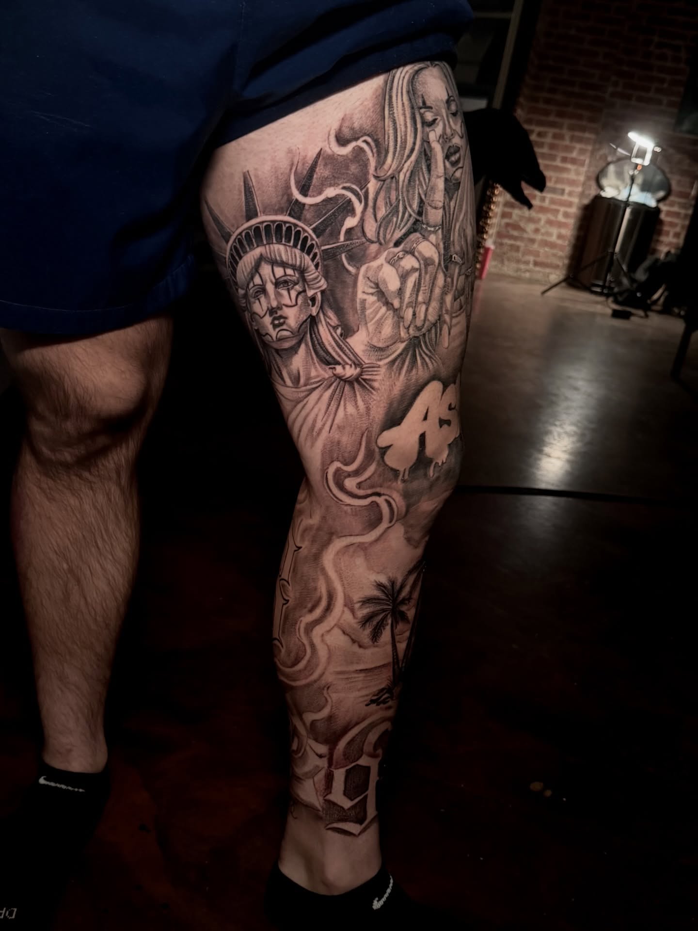 Statue of liberty and woman black and grey tattoo on the leg by Tattoo Artist