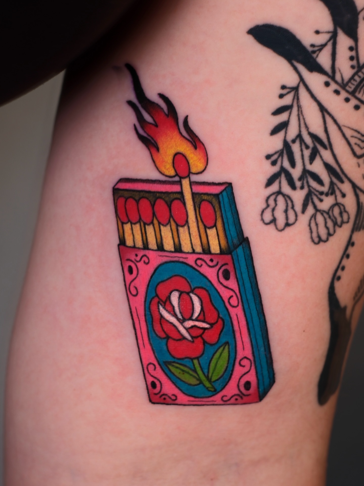 Matchbox with burning match American traditional tattoo on the upper arm by Mallory Murphy, Denton, Texas