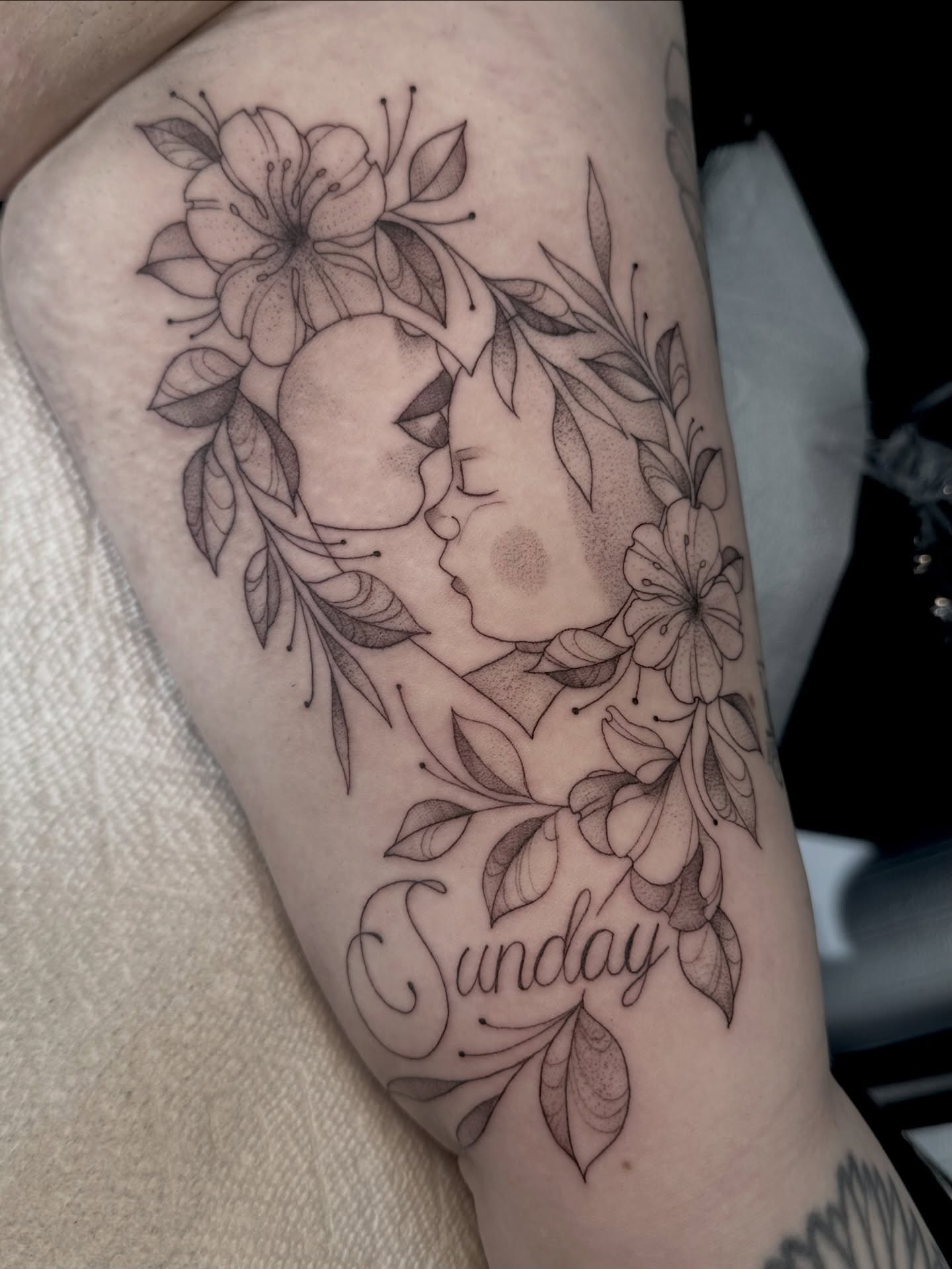 Kissing couple with floral wreath realism tattoo on the forearm by Ghost