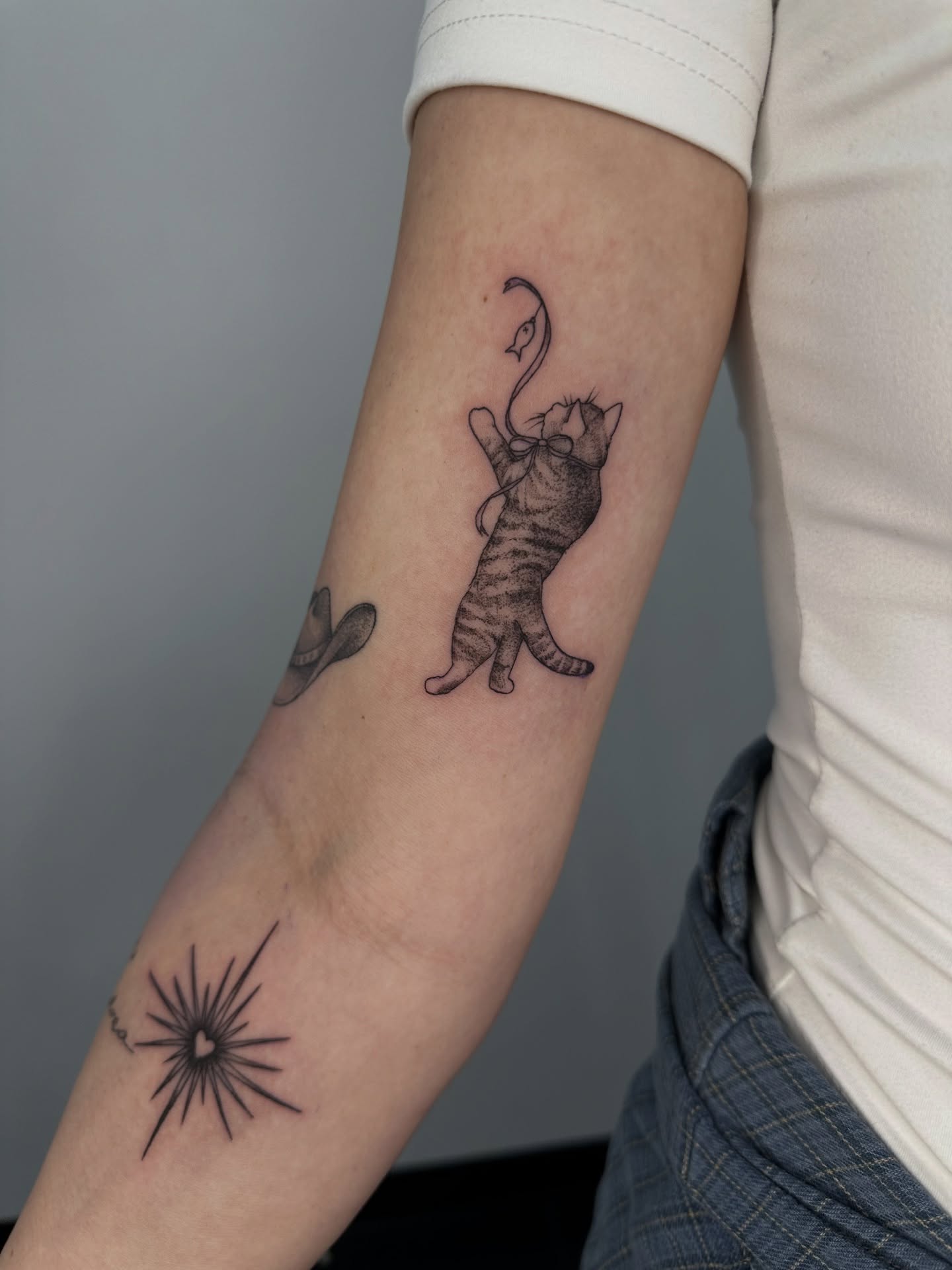 Cat and hat black and grey tattoo on the forearm by ๐ฌ๐๐๐ฏ๐ ๐ฆ ๐๐ฉ๐ฆ๐ท๐๐๐ข๐ฑ๐ฅ ๐ซง๐ผ, Joplin, Missouri