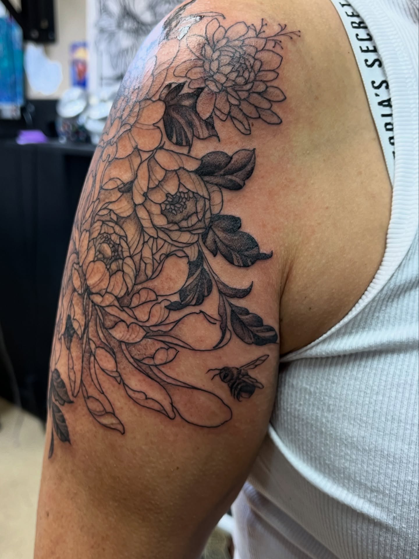 Floral arrangement black and grey tattoo on the upper arm by Tabitha Mathis