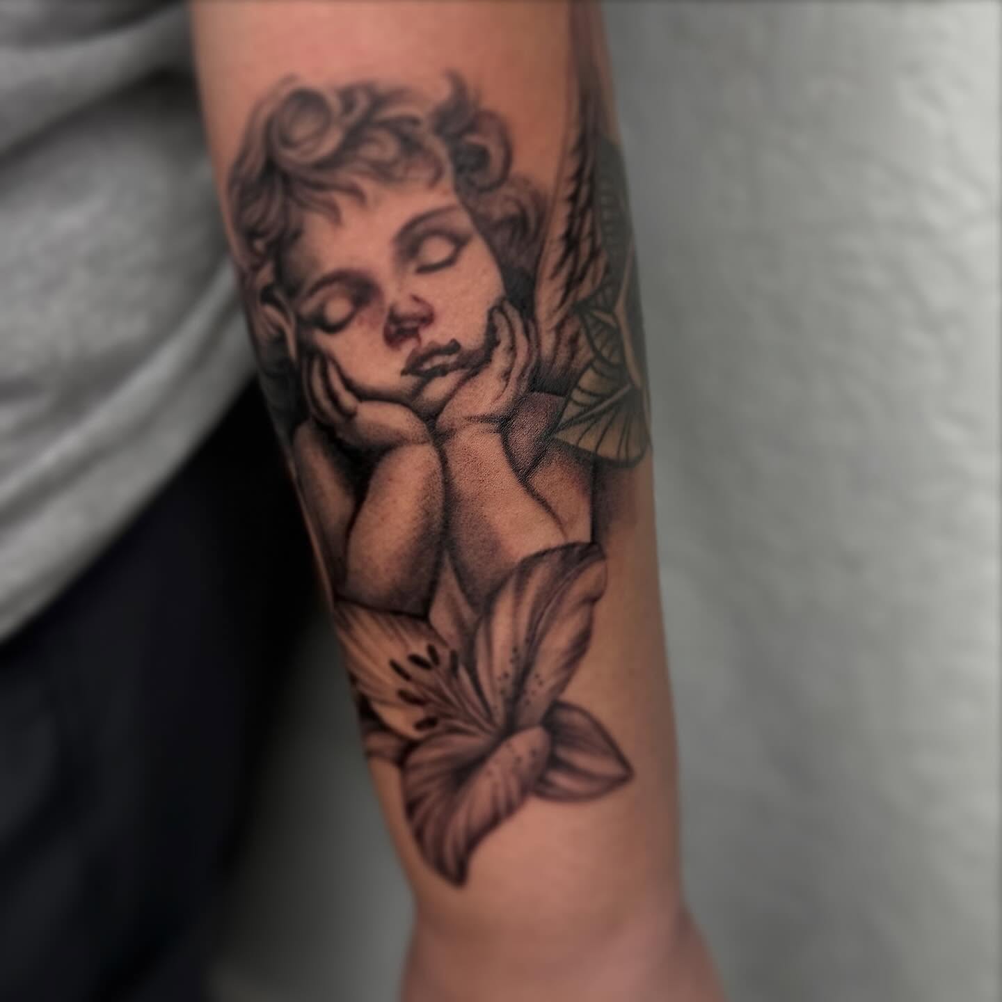 Angel with lily realism tattoo on the forearm by Jocelyn