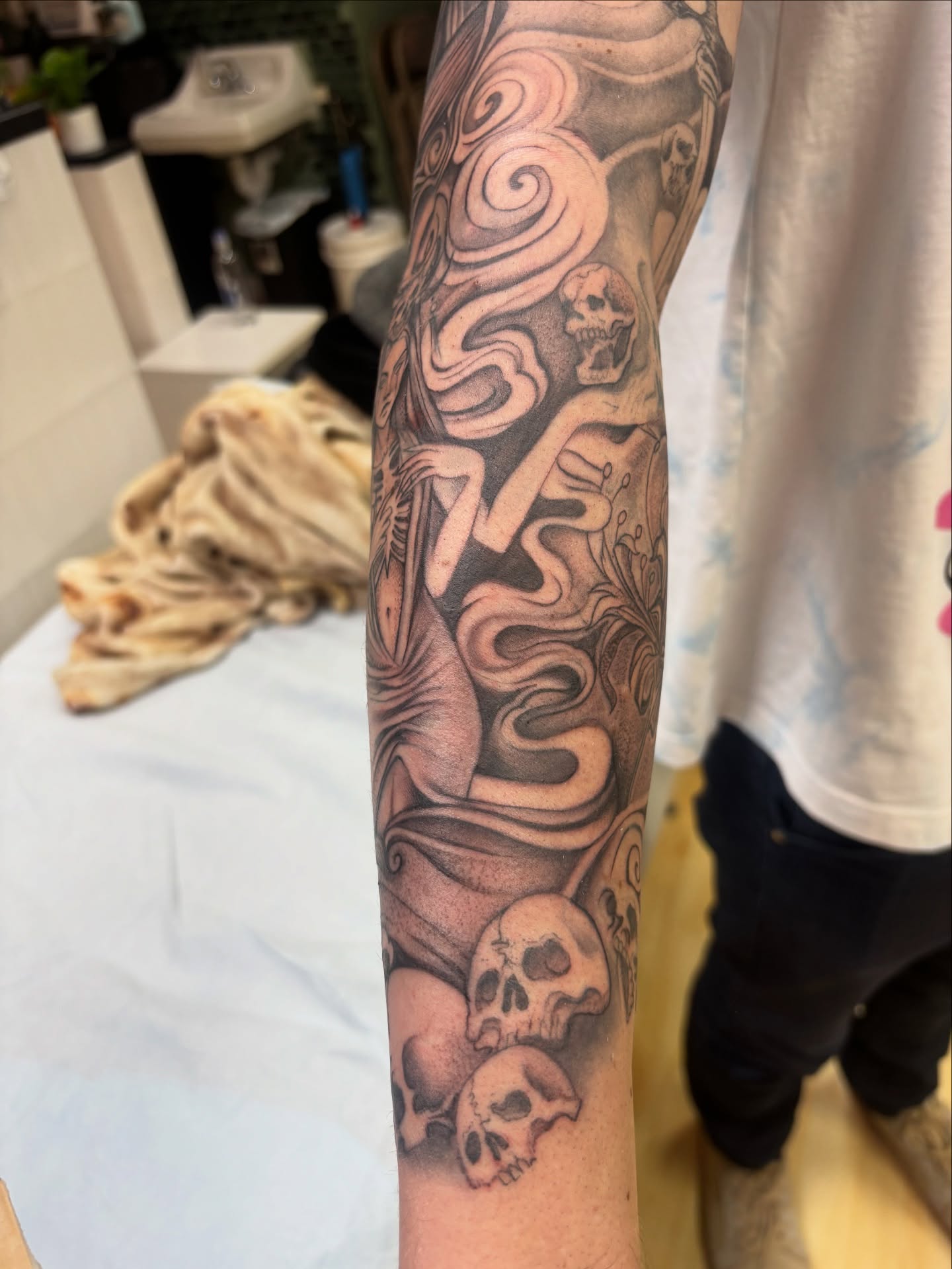 Skulls and swirling smoke realism tattoo on the forearm by Ivanna