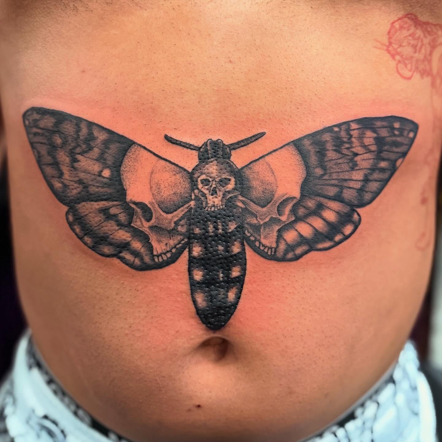 Moth with skulls dotwork tattoo on the torso by Joshua Ware, Alvarado, Texas