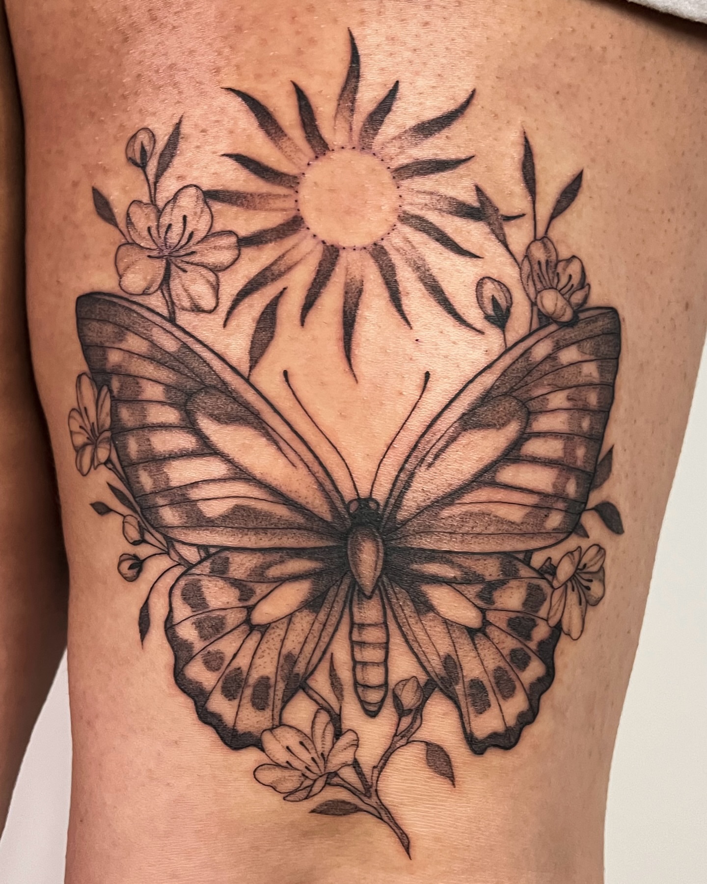 Butterfly and sun realism tattoo on the thigh by Mikayla Sue
